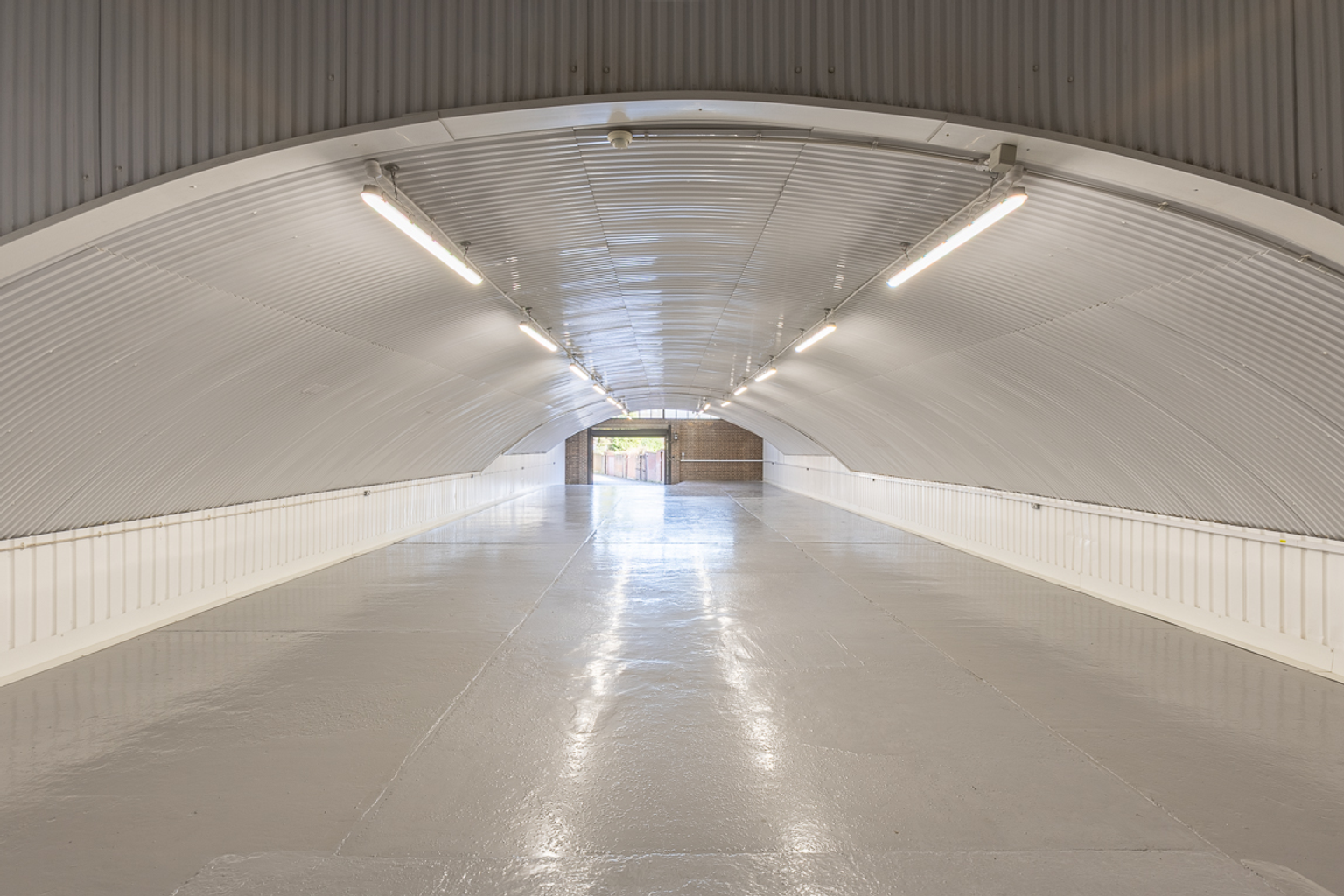 An empty arch with white lining and a WC cubicle to the back.