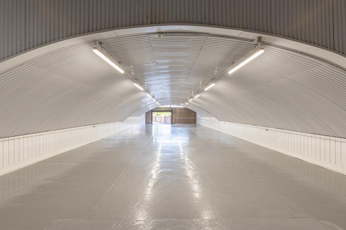 An empty arch with white lining and a WC cubicle to the back.
