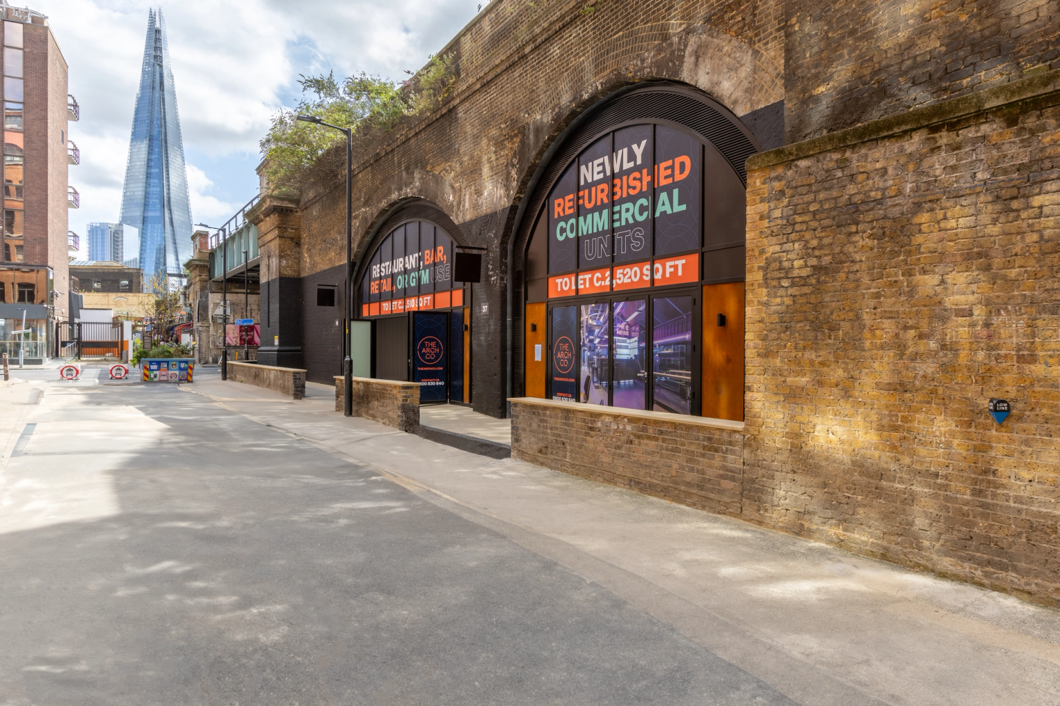 A street scene with brick archways featuring "Newly Refurbished Commercial Units" signs, and The Shard visible in the background.