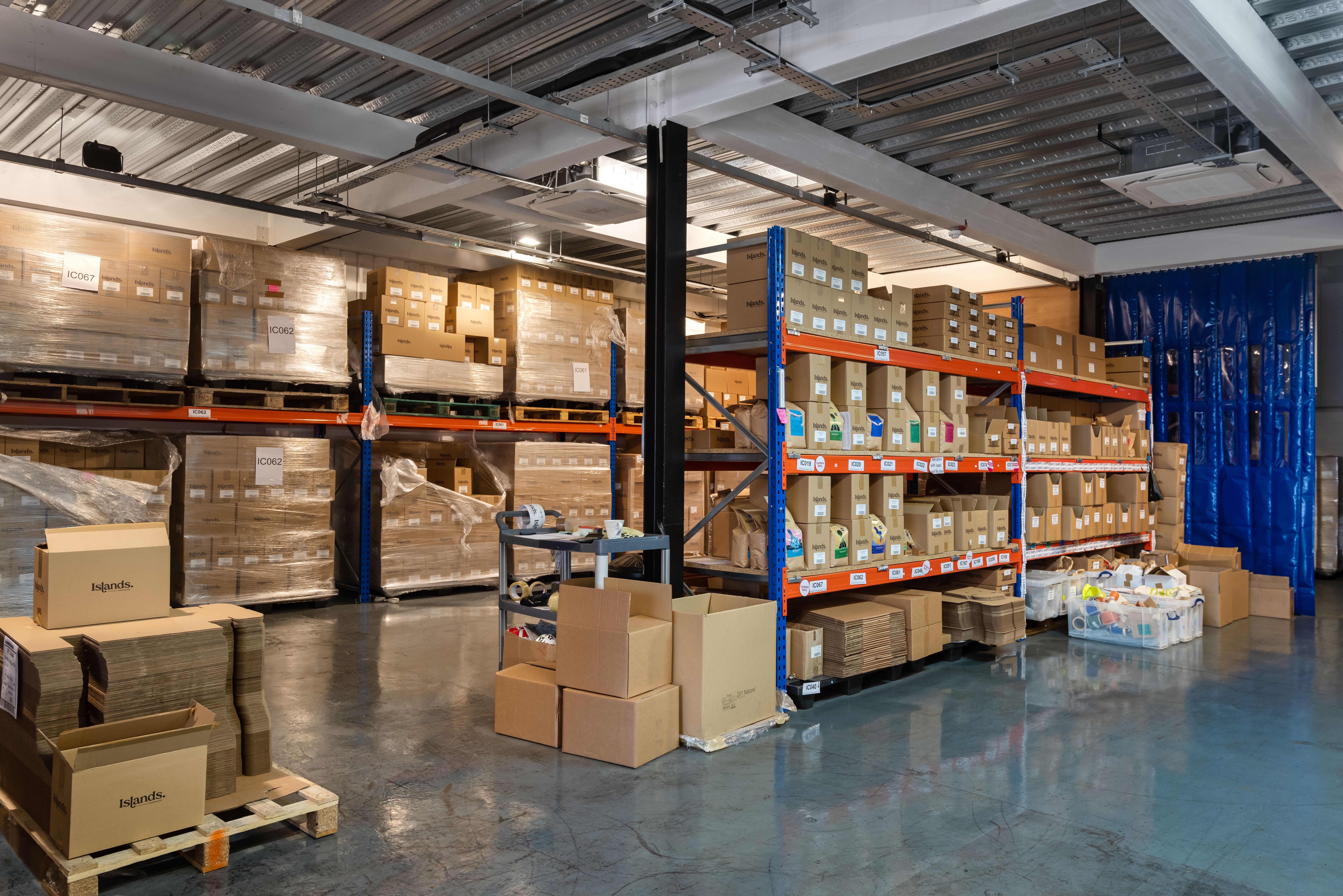 A warehouse filled with boxes on pallets and industrial shelving.