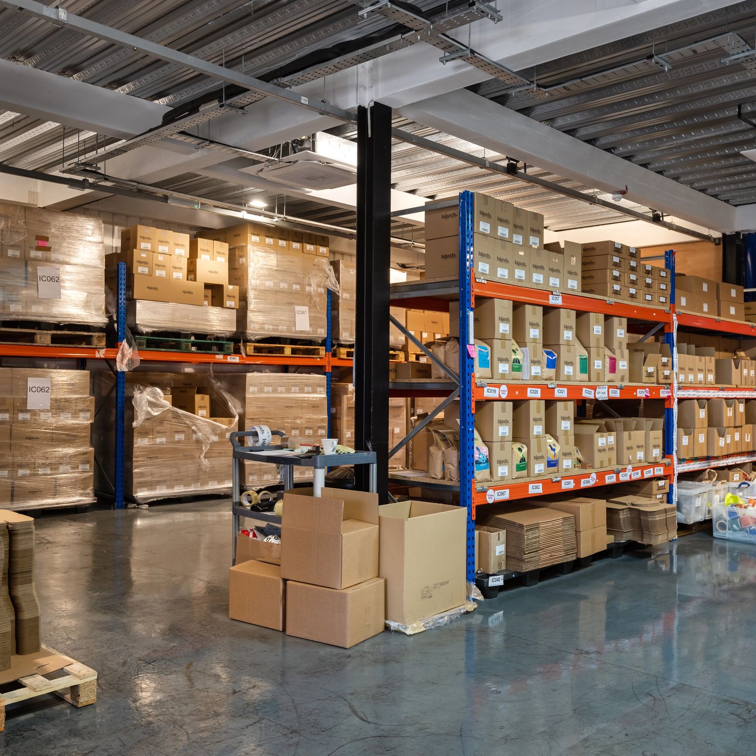 A warehouse filled with boxes on pallets and industrial shelving.