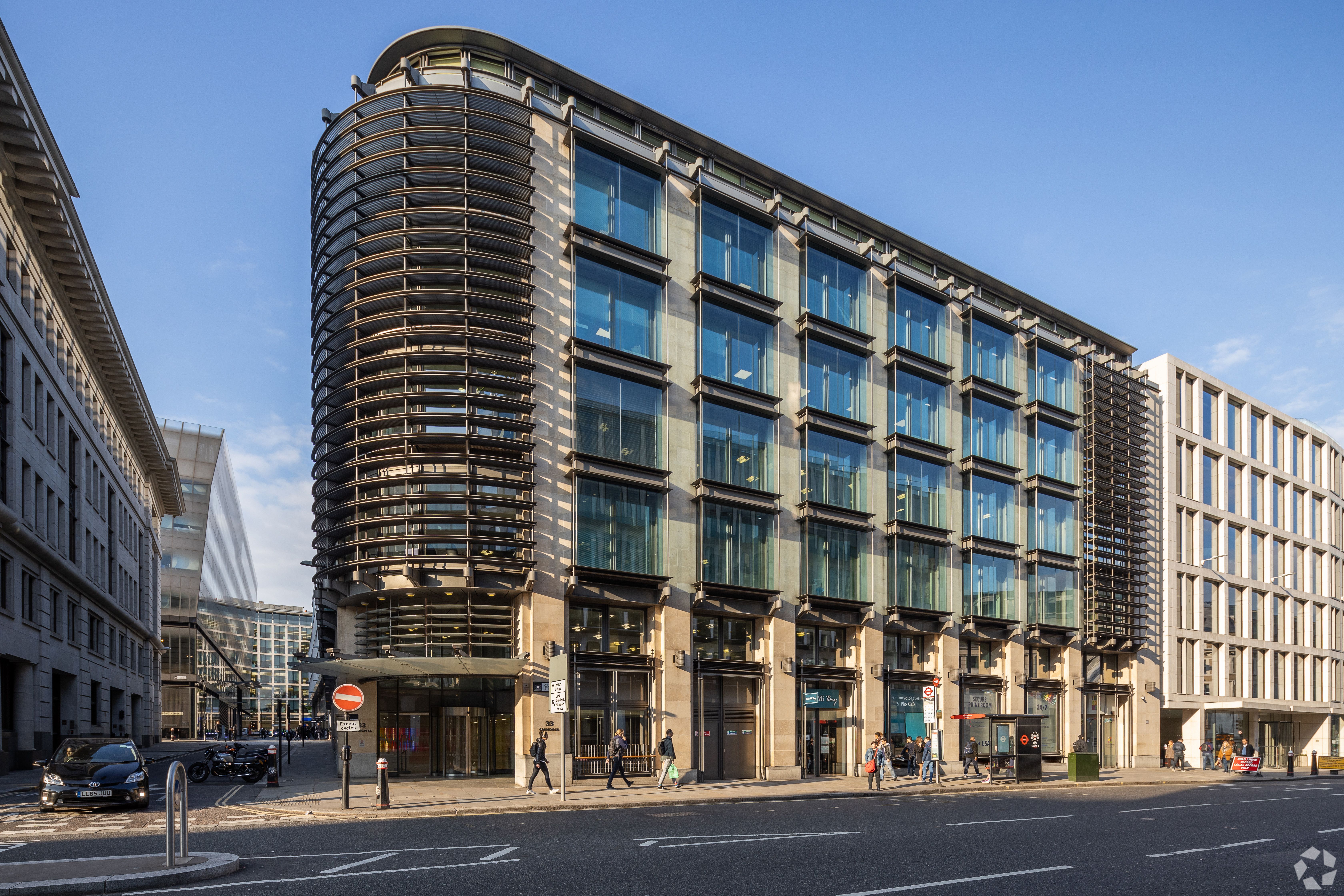 A modern building with a curved glass facade and horizontal louvers on a city street.