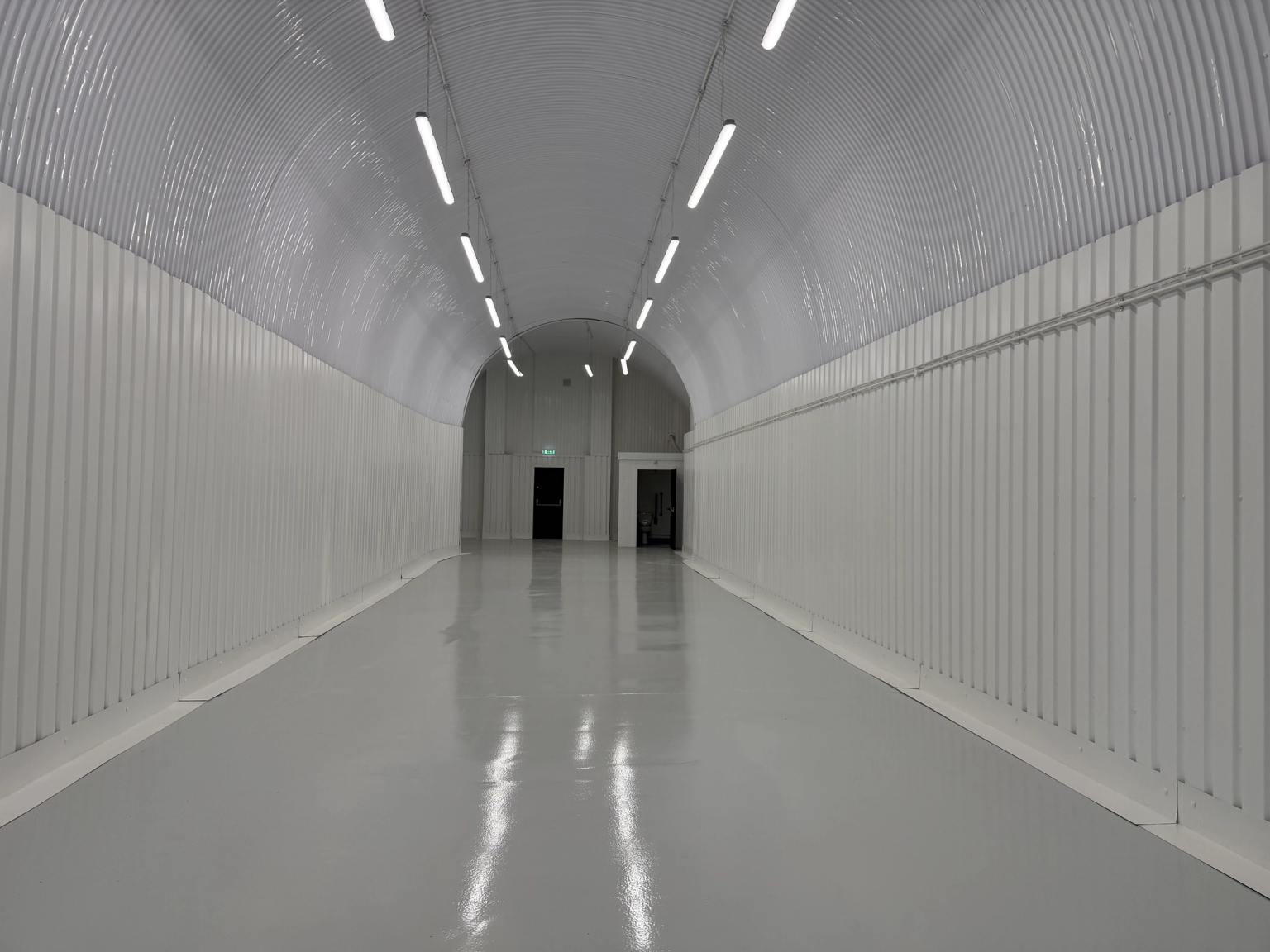 An empty arch with white lining and a WC cubicle to the back.