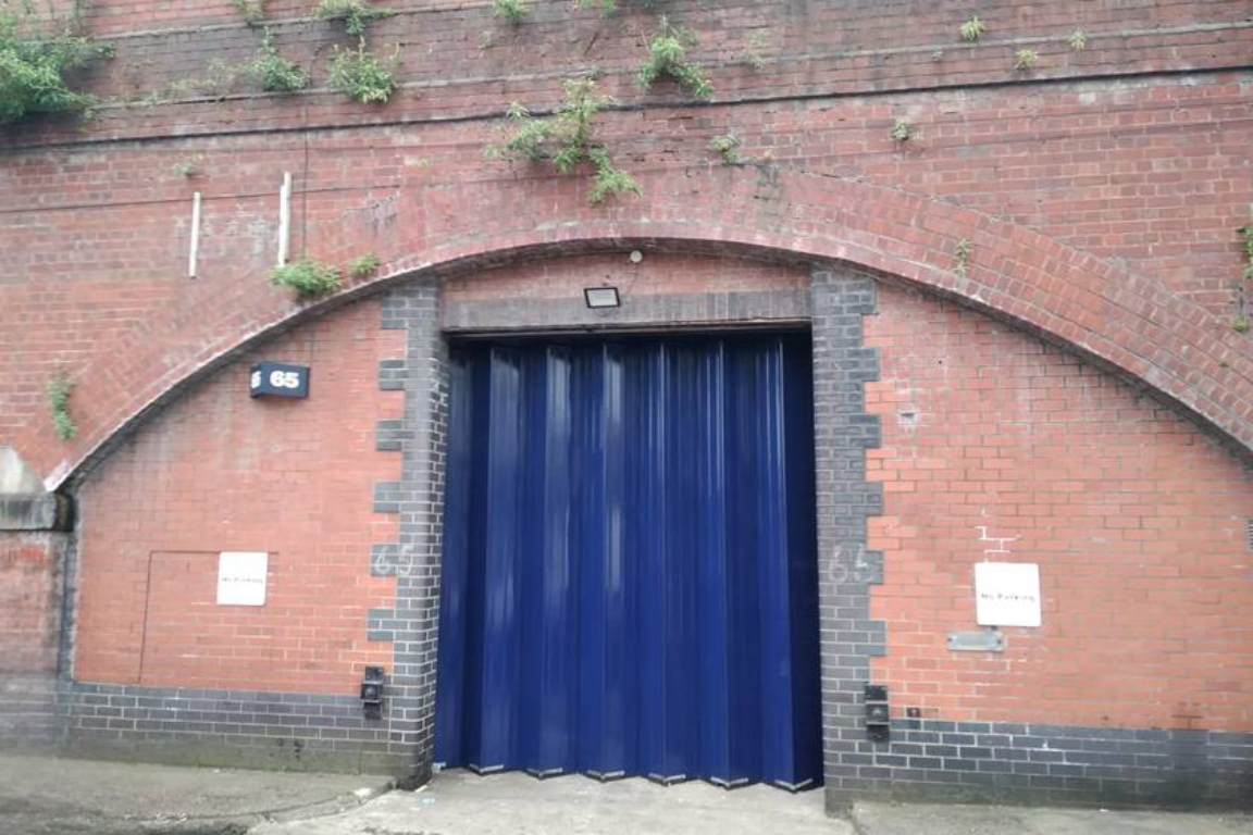 The front of an arch with a closed metal concertina door that can be pulled back fully.