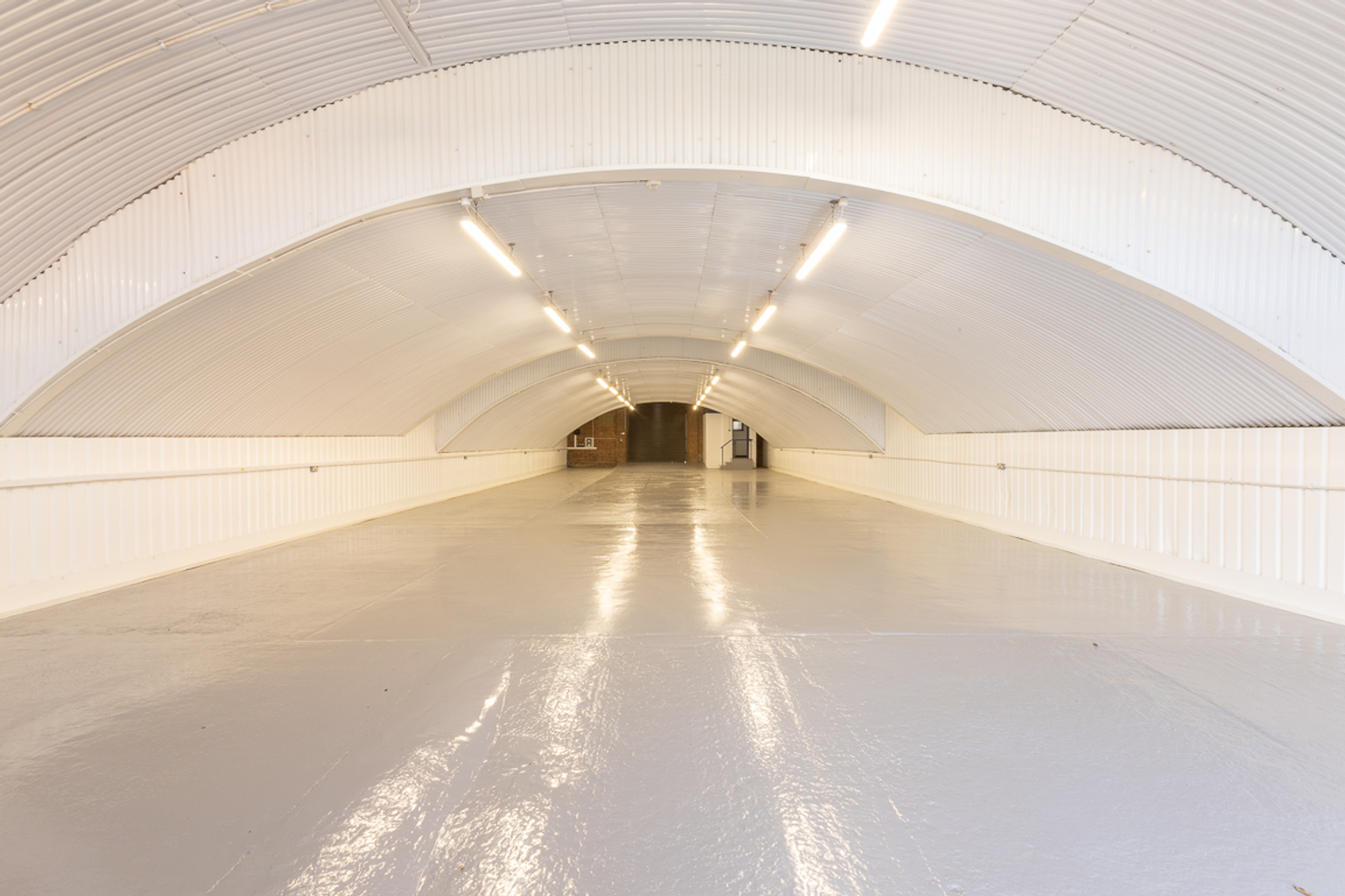 An empty arch with white lining and a WC cubicle to the back.