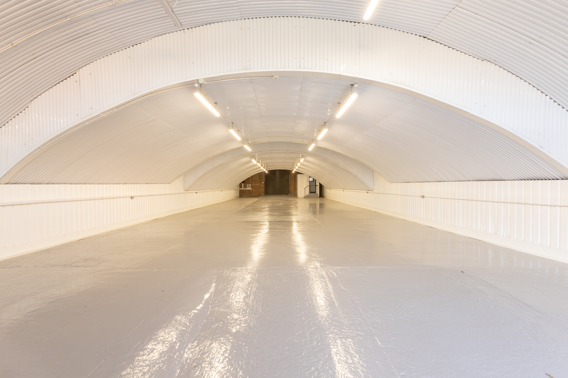 An empty arch with white lining and a WC cubicle to the back.