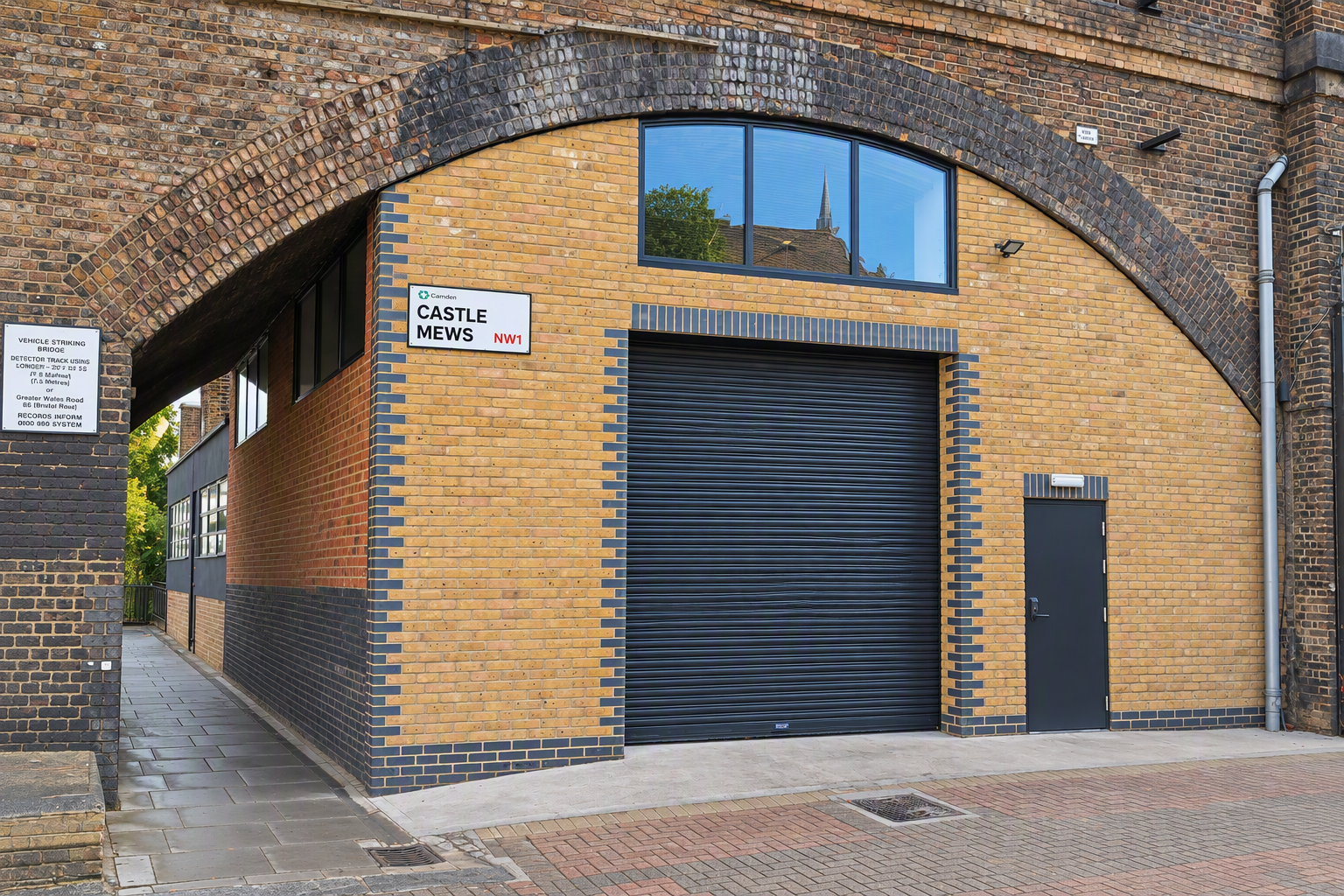 The front of an arch, with high level glazing, a closed electric roller shutter entrance big enough for vehicle access, and a pedestrian door.