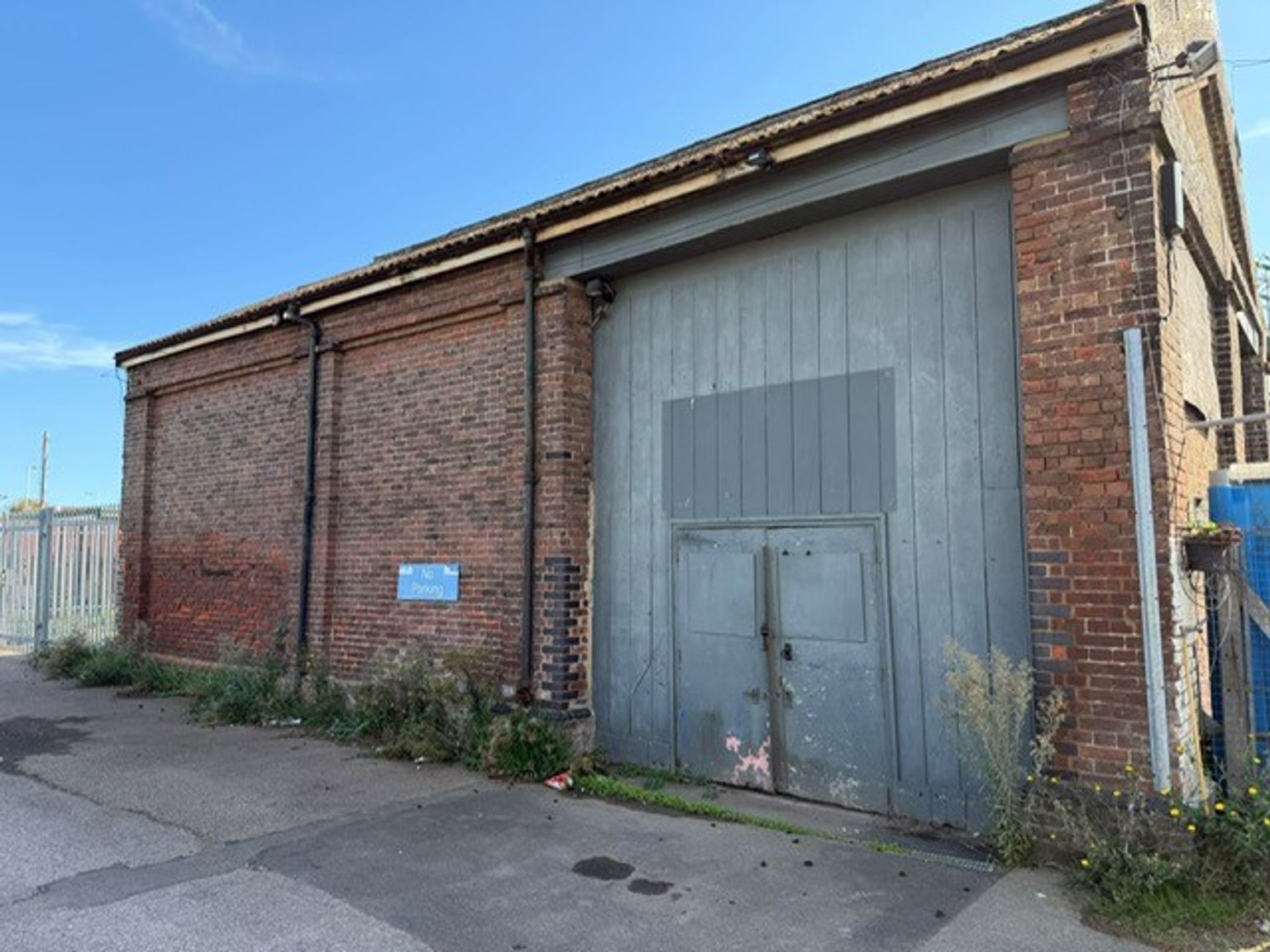 The front of a warehouse unit, with a closed electric roller shutter entrance big enough for vehicle access, and a pedestrian door.