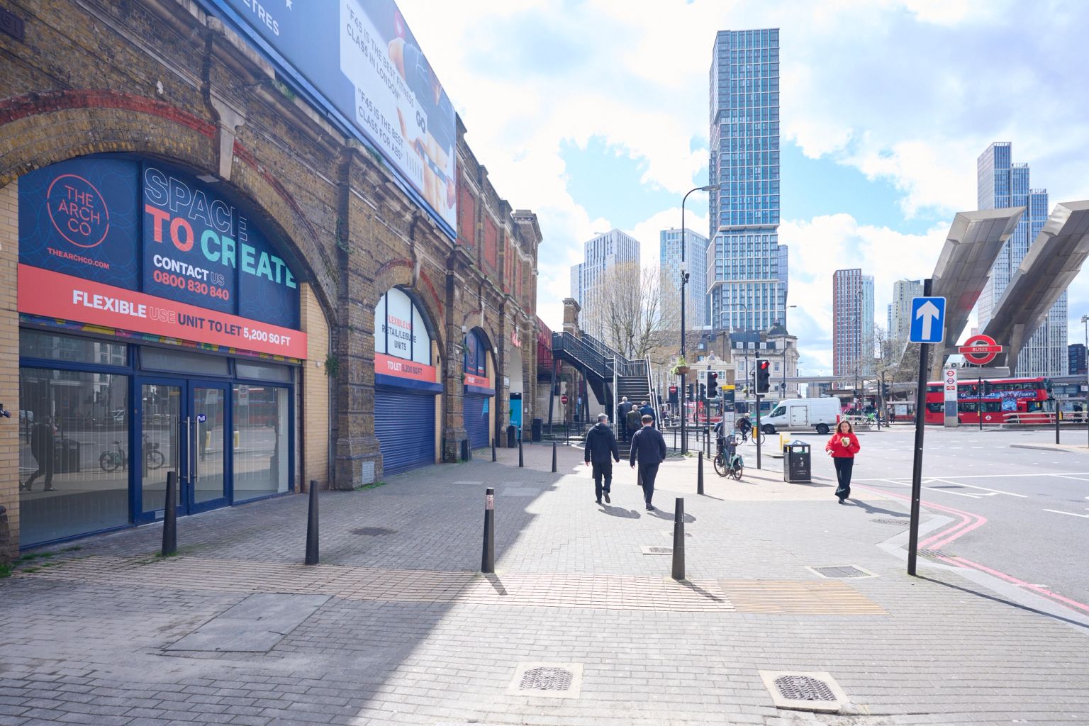 Renovated brick railway arches with blue doors, one open to a modern commercial interior.