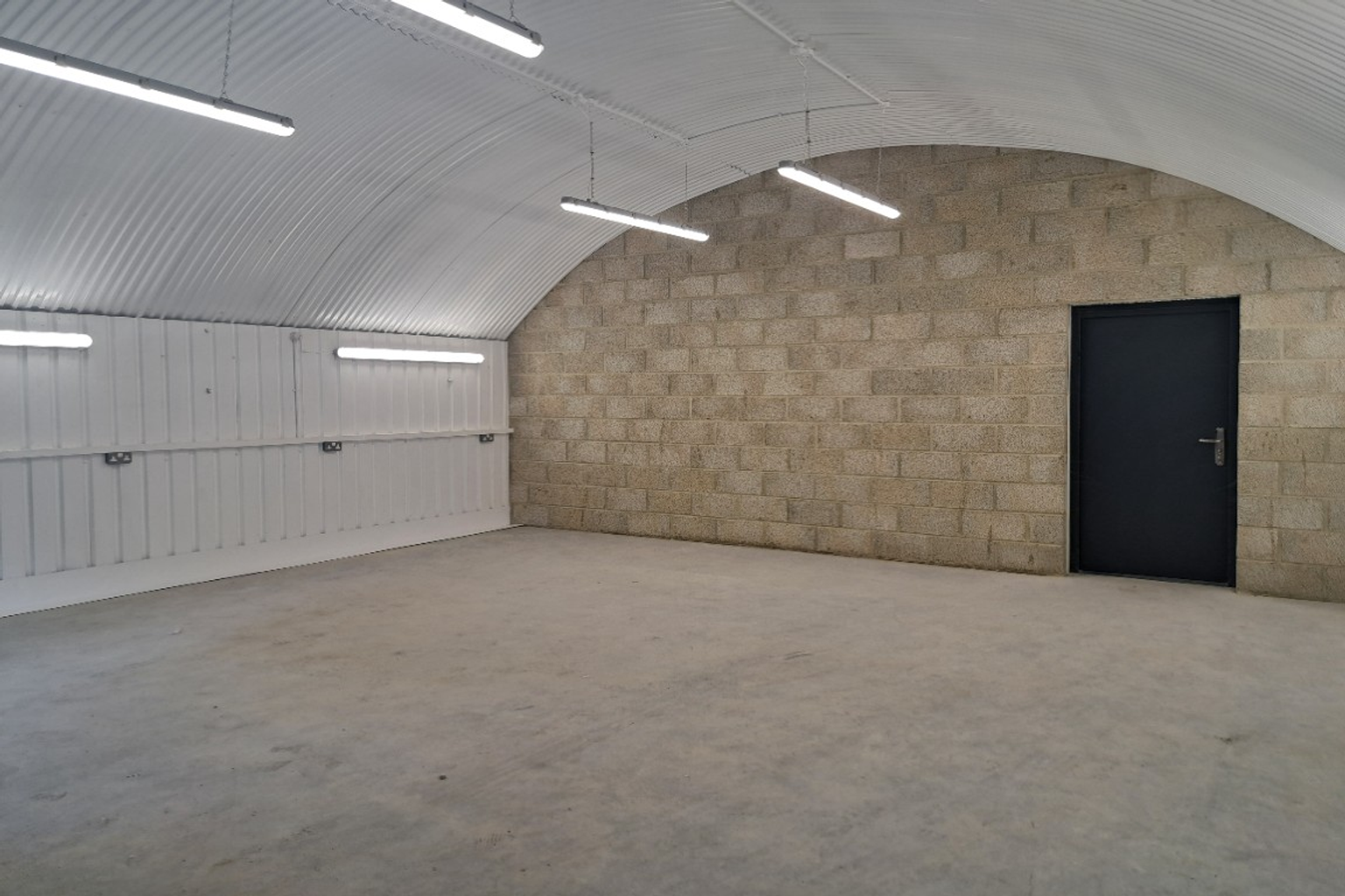 An empty arch with white lining and a fire escape door at the back.