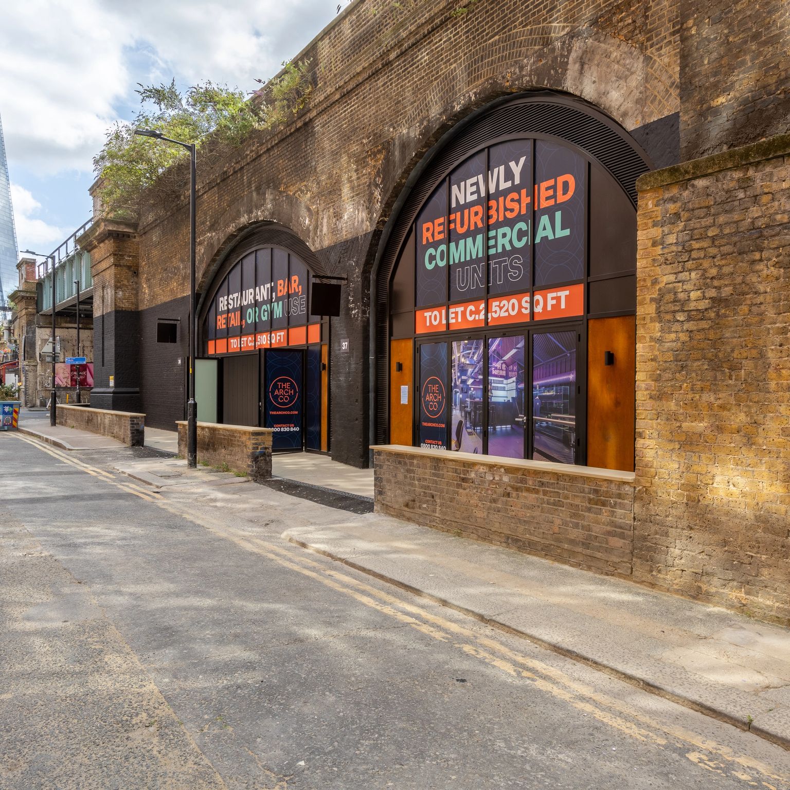 Quiet urban street with brick railway arches promoting commercial units, The Shard visible in the distance.