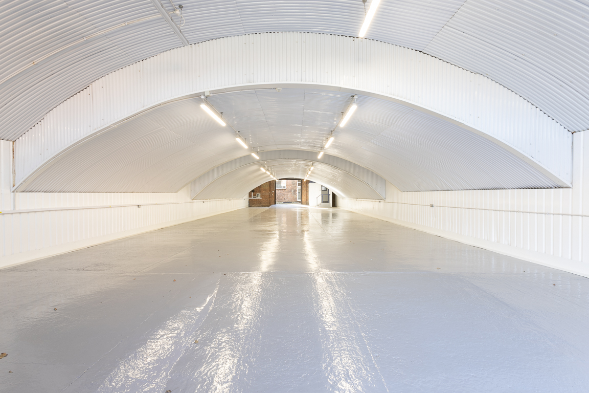 An empty arch with white lining and a WC cubicle to the back.