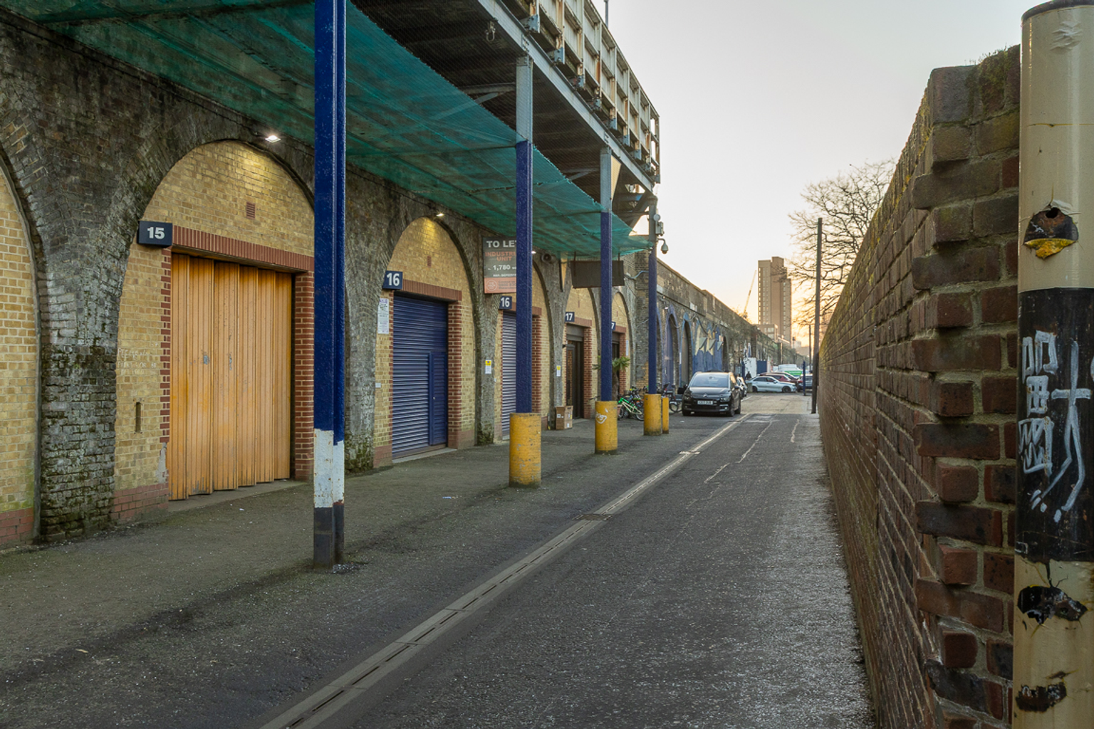 An estate, with multiple arches next to each other. The arches have closed electric roller shutter entrances.