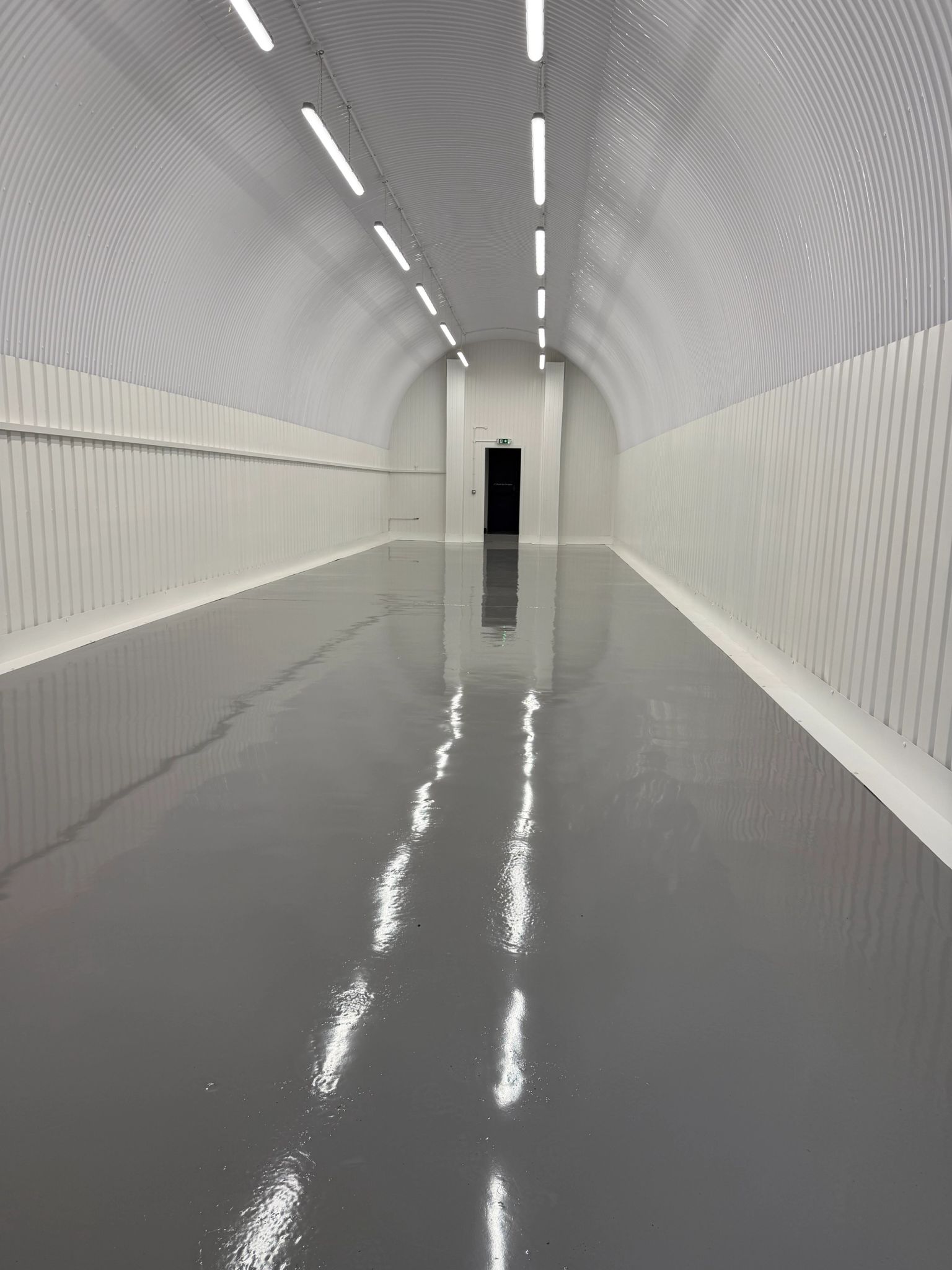 An empty arch with white lining and a WC cubicle to the front.