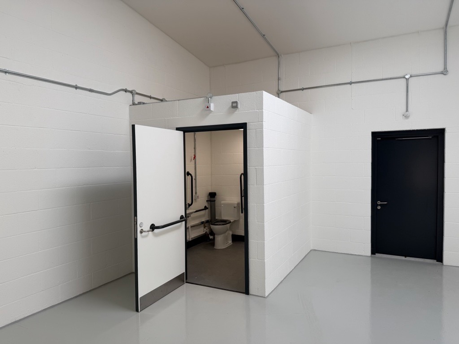 An empty arch with white lining and a WC cubicle to the back.