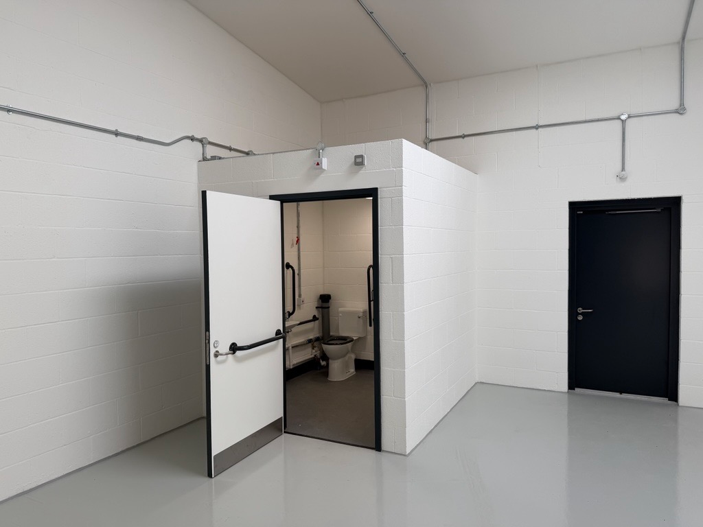 An empty arch with white lining and a WC cubicle to the back.