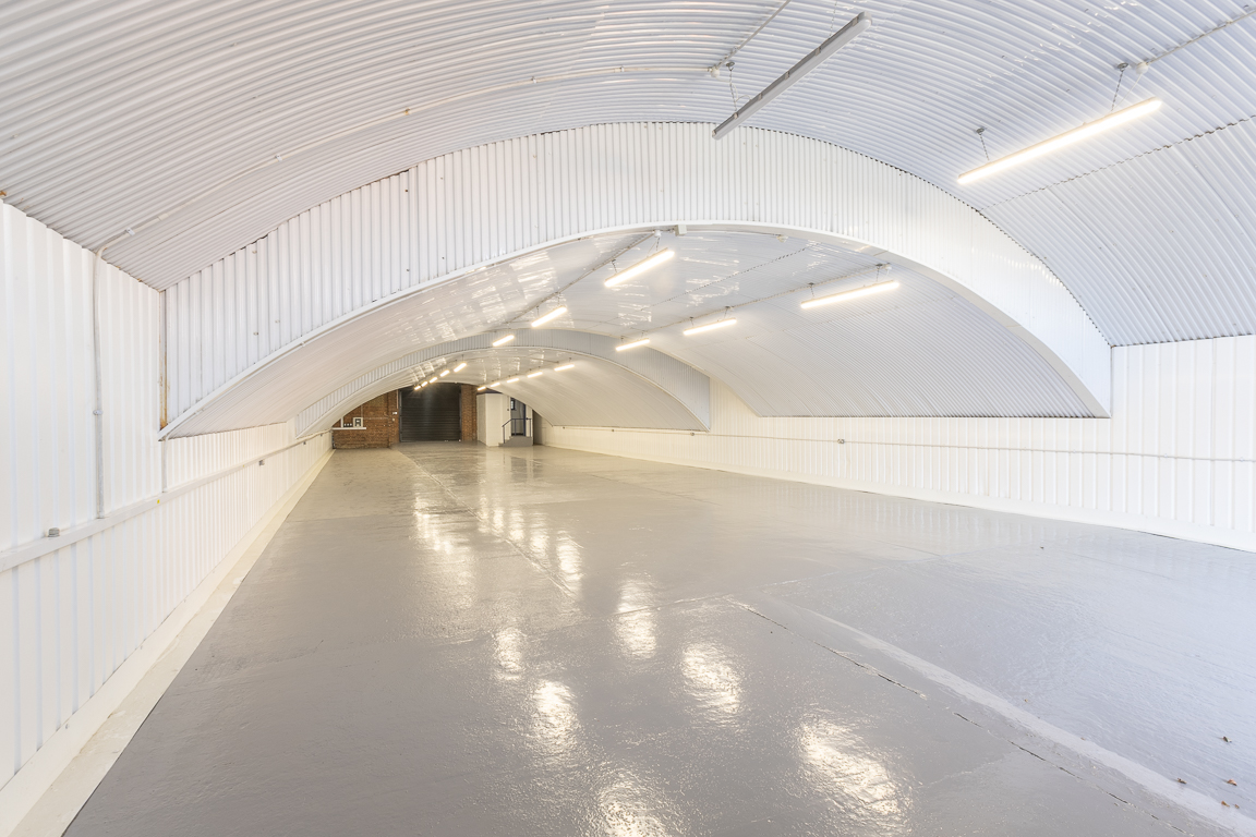 An empty arch with white lining and a WC cubicle to the back.