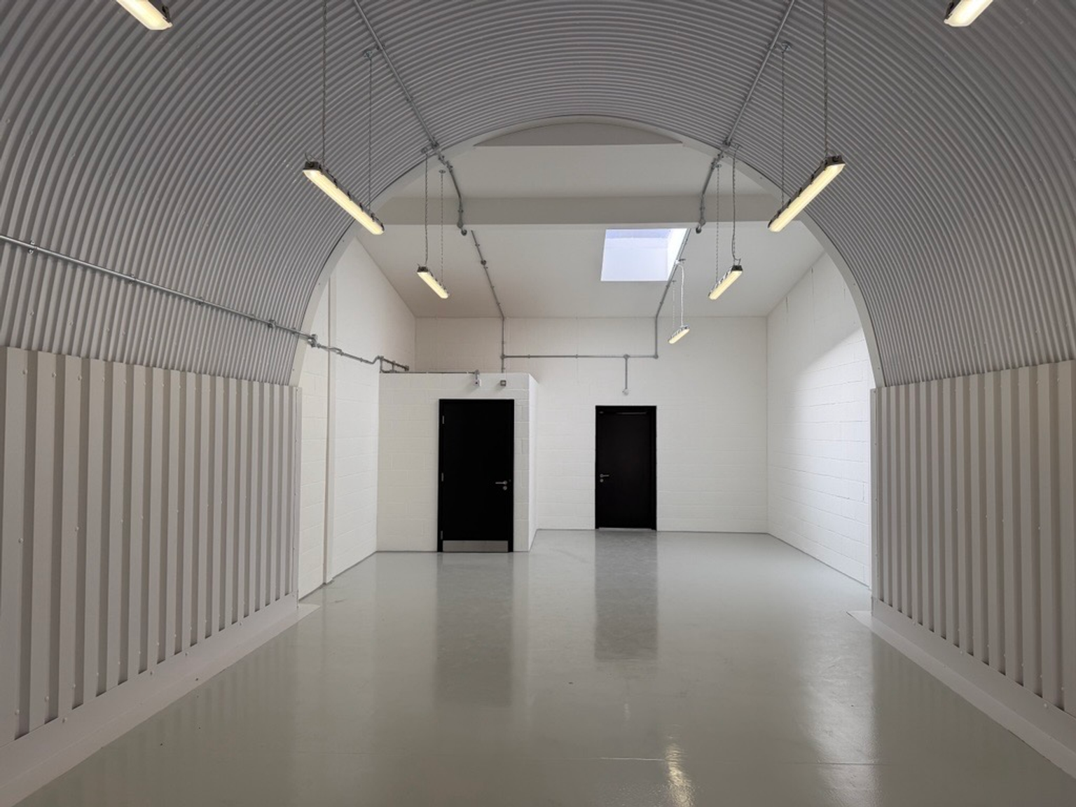 An empty arch with white lining and a fire escape door at the back.