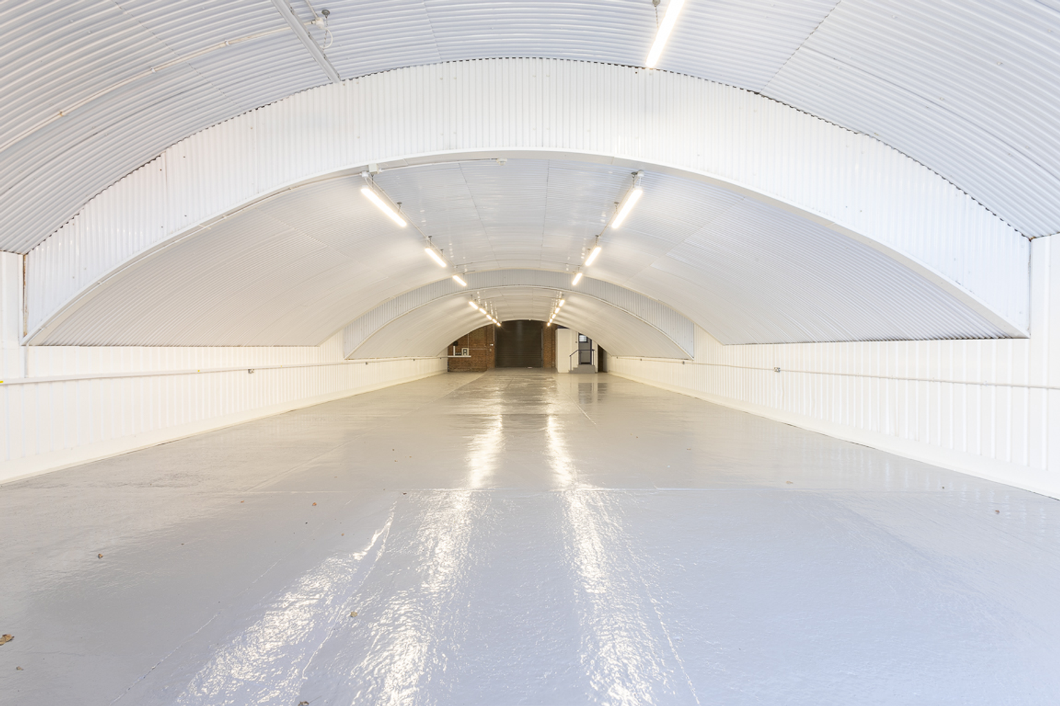 An empty arch with white lining and a WC cubicle to the back.