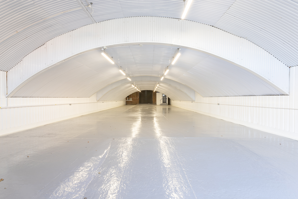 An empty arch with white lining and a WC cubicle to the back.