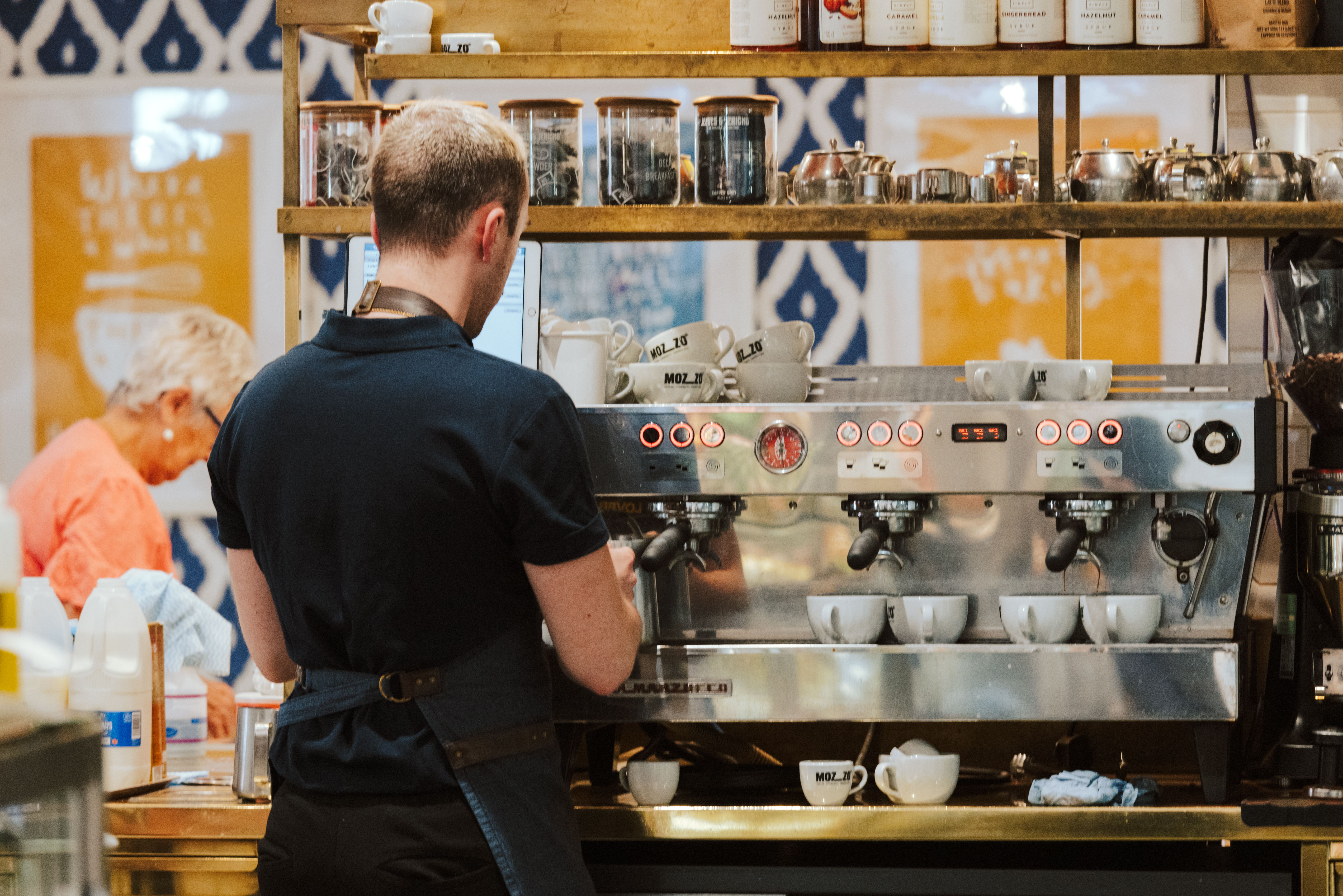 A barista makes coffee at an espresso machine in a cafe.