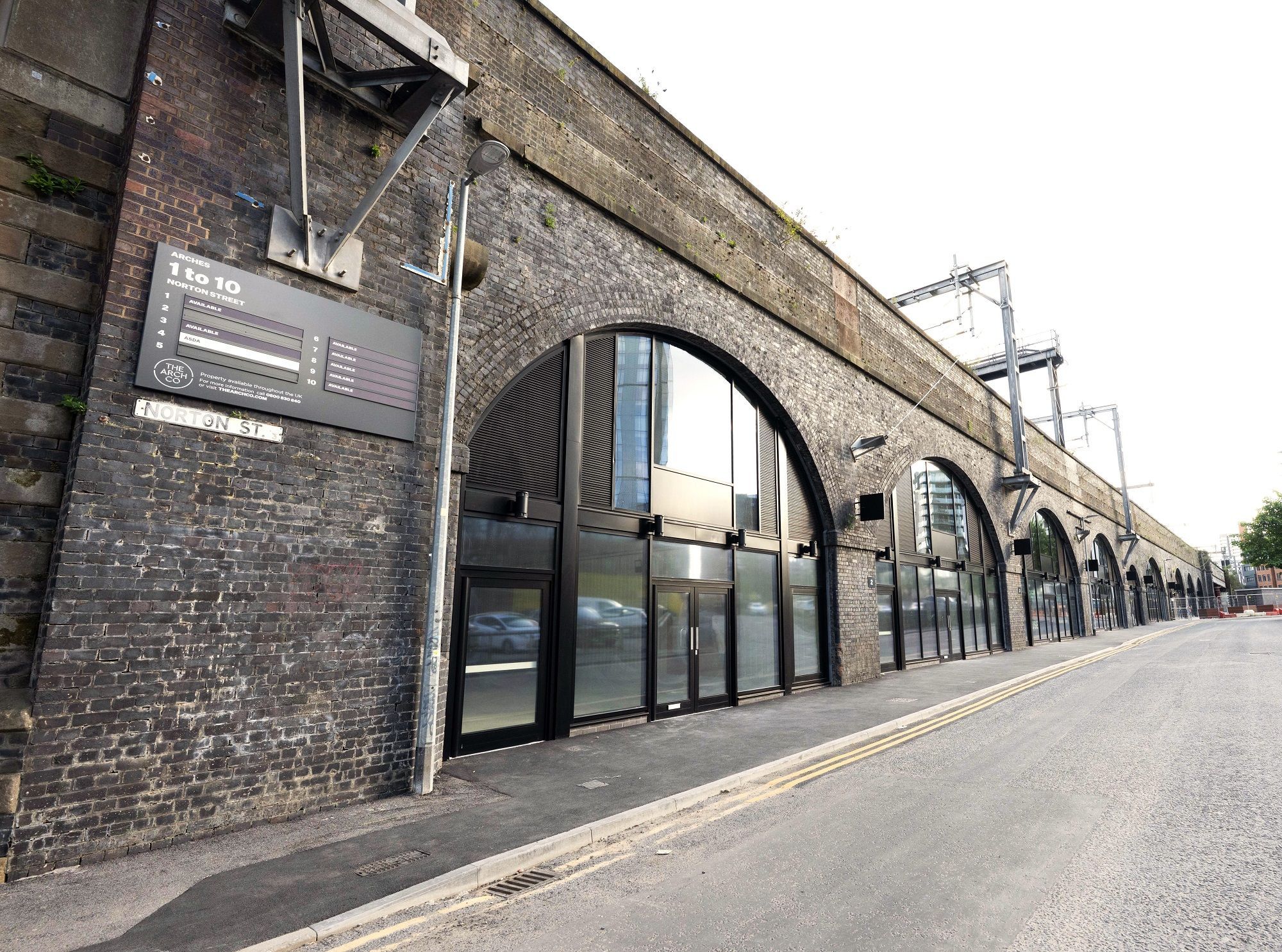 Modernized brick railway arches with glass storefronts along Norton Street.