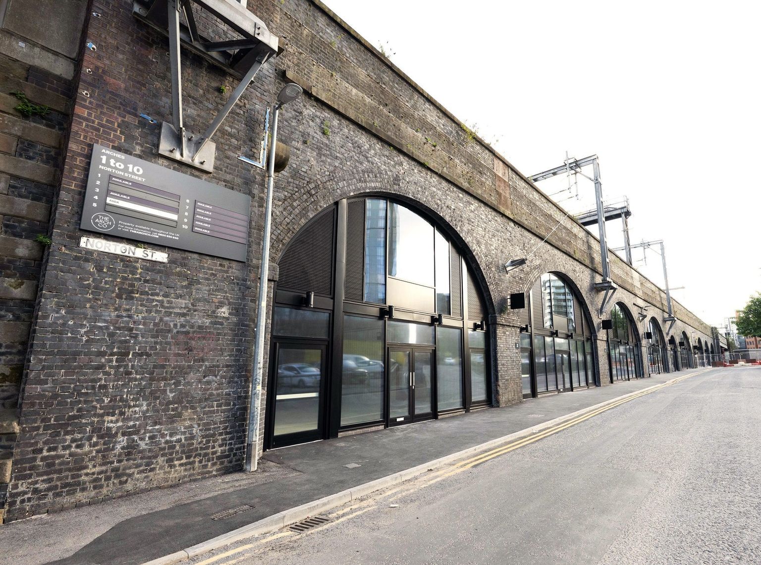 Modernized brick railway arches with glass storefronts along Norton Street.