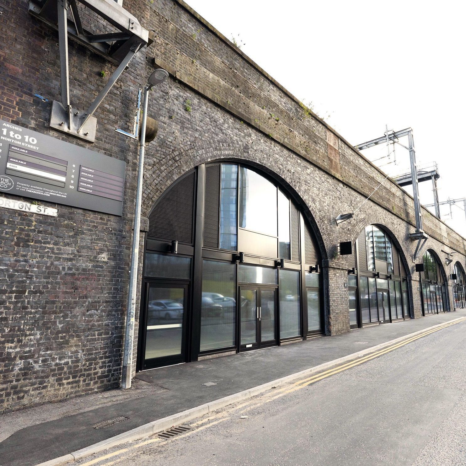 Modernized brick railway arches with glass storefronts along Norton Street.