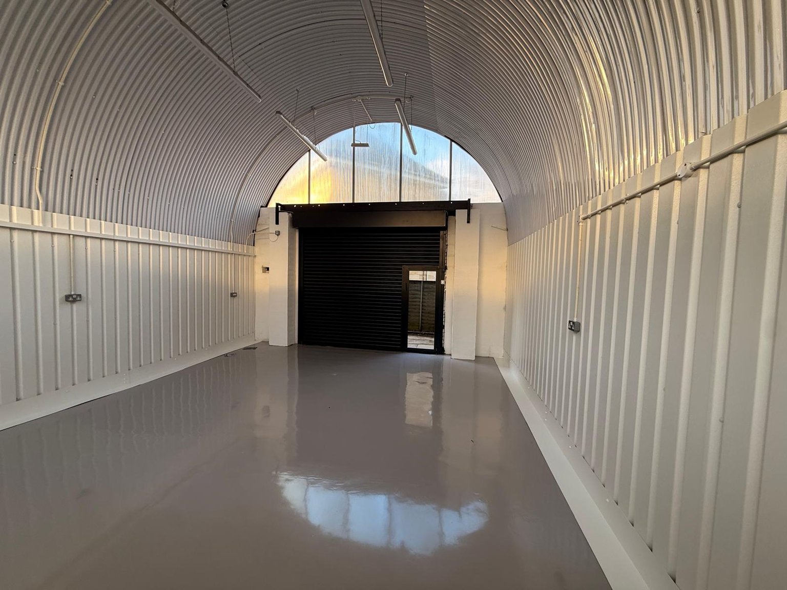 An empty arch with white lining and full height glazing to the front.