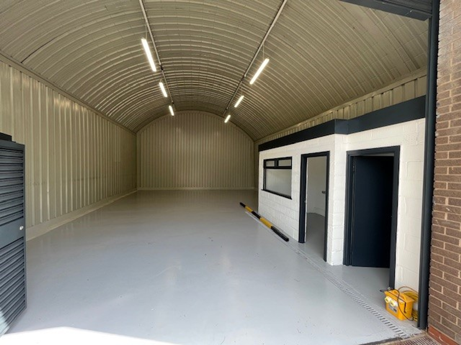 An empty arch with white lining and a WC cubicle to the front.