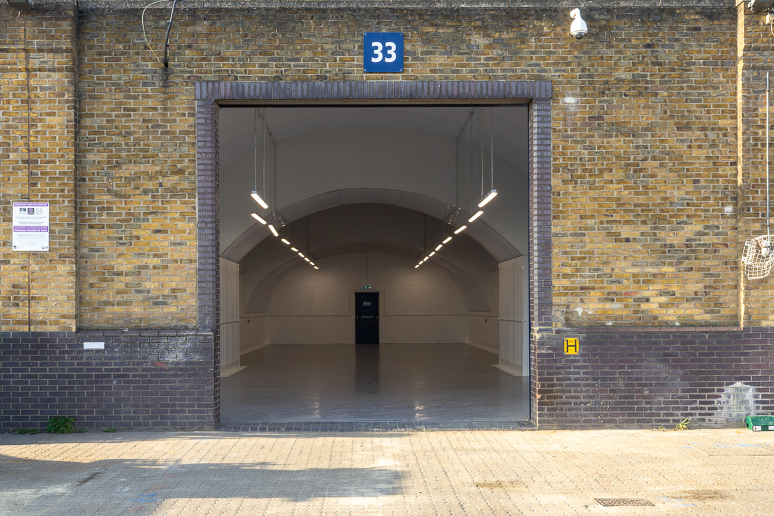 The front of a warehouse unit, with an open electric roller shutter entrance big enough for vehicle access, and a pedestrian door.