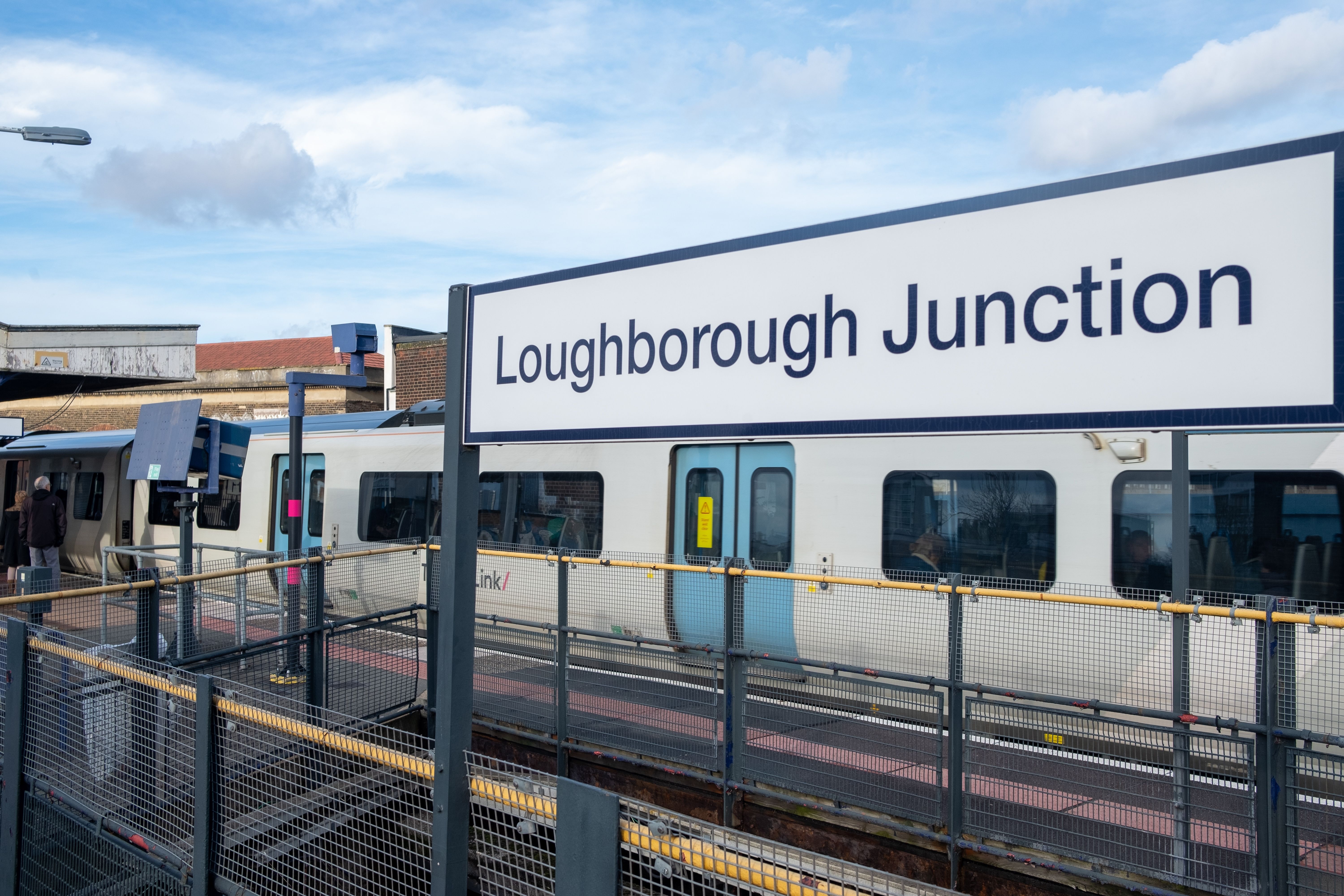 A train at Loughborough Junction station platform under a cloudy sky.