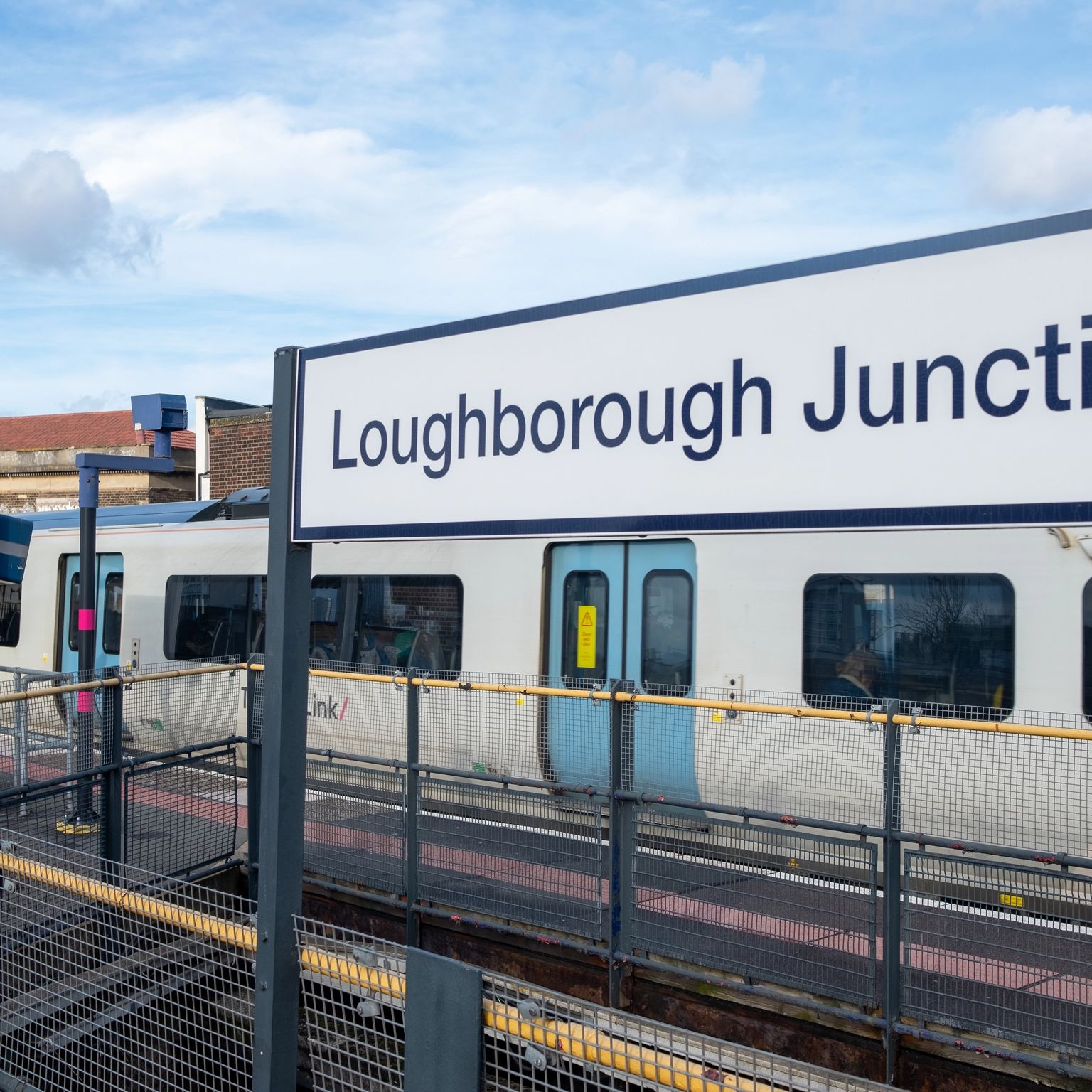 A train at Loughborough Junction station platform under a cloudy sky.