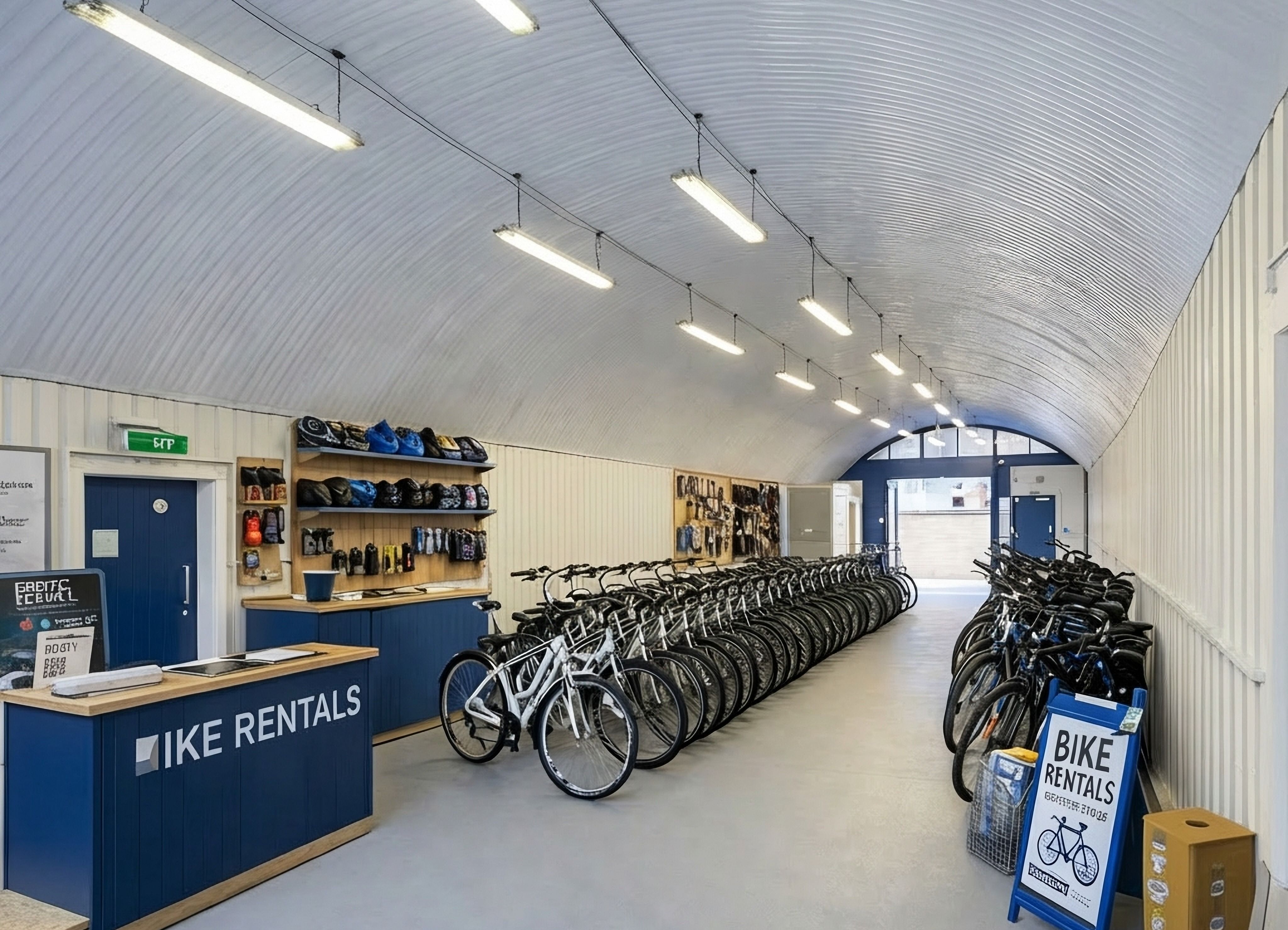 Interior of a bike rental facility with a vaulted ceiling, a reception counter, and many bicycles arranged in rows.
