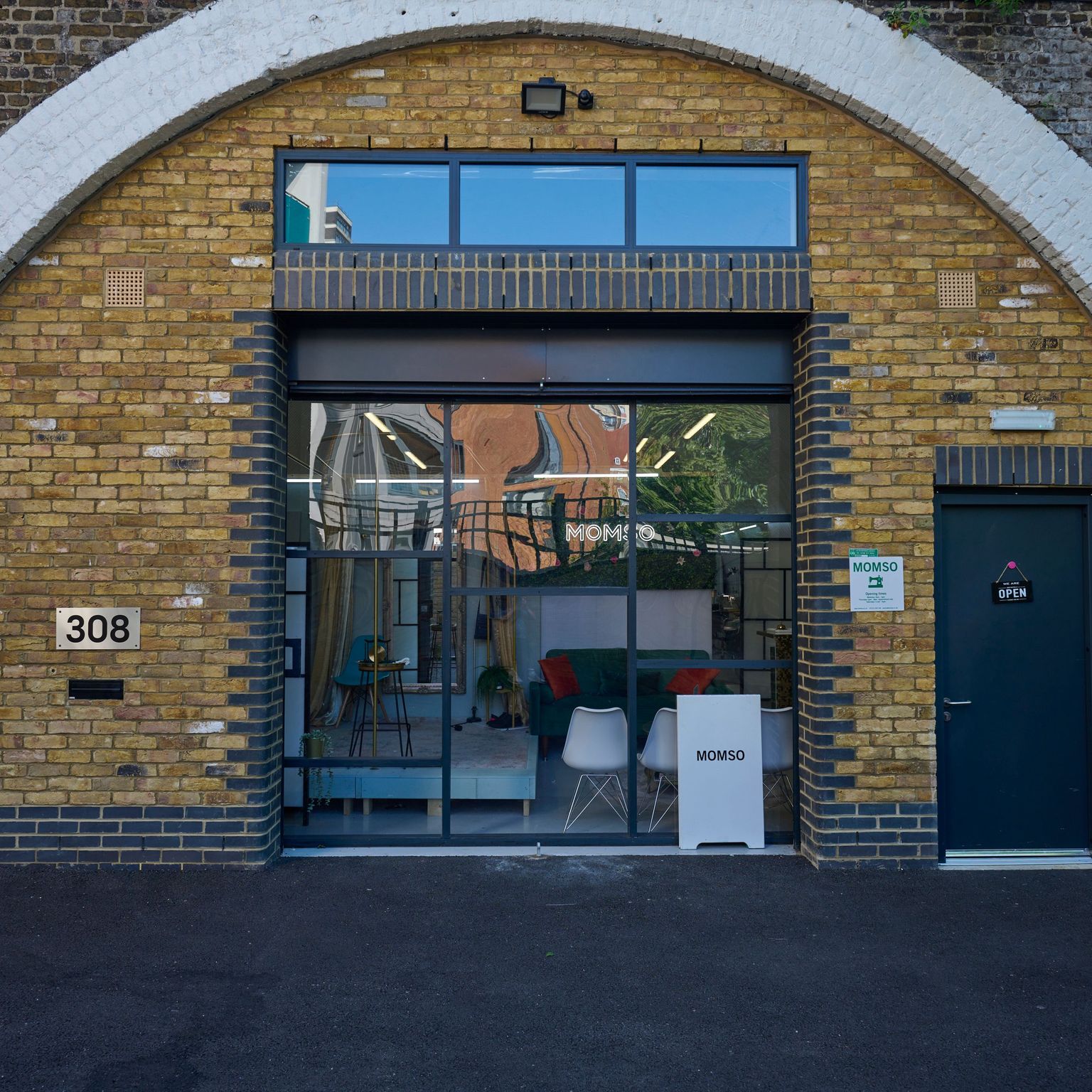 A modern shopfront displaying furniture inside a yellow brick railway arch, numbered 308.