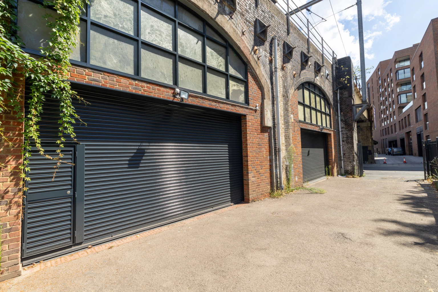 The front of an arch, with high level glazing, a closed electric roller shutter entrance big enough for vehicle access, and a pedestrian door.