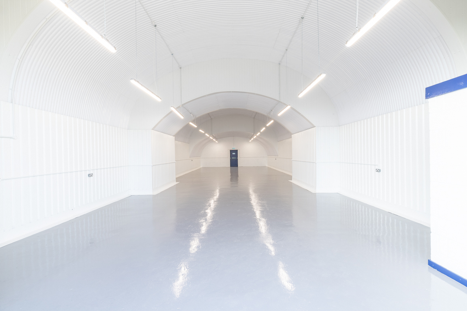 An empty arch with white lining and a WC cubicle to the back.