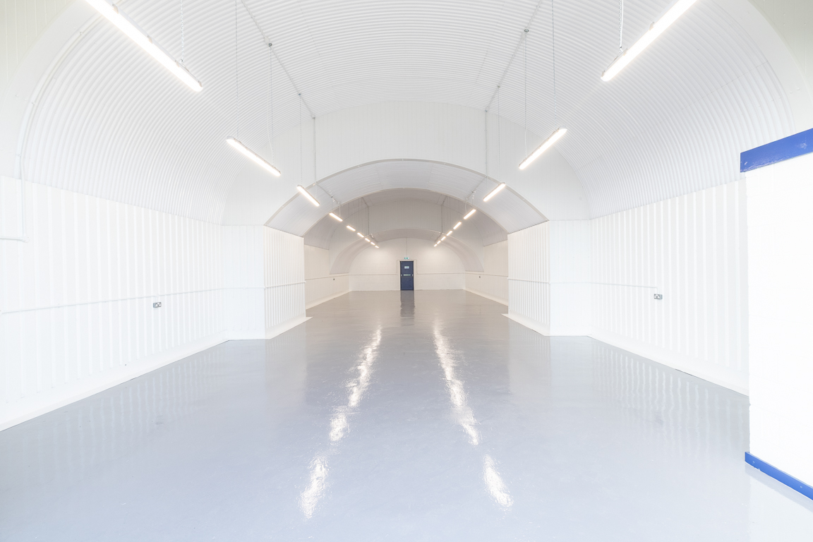 An empty arch with white lining and a WC cubicle to the back.