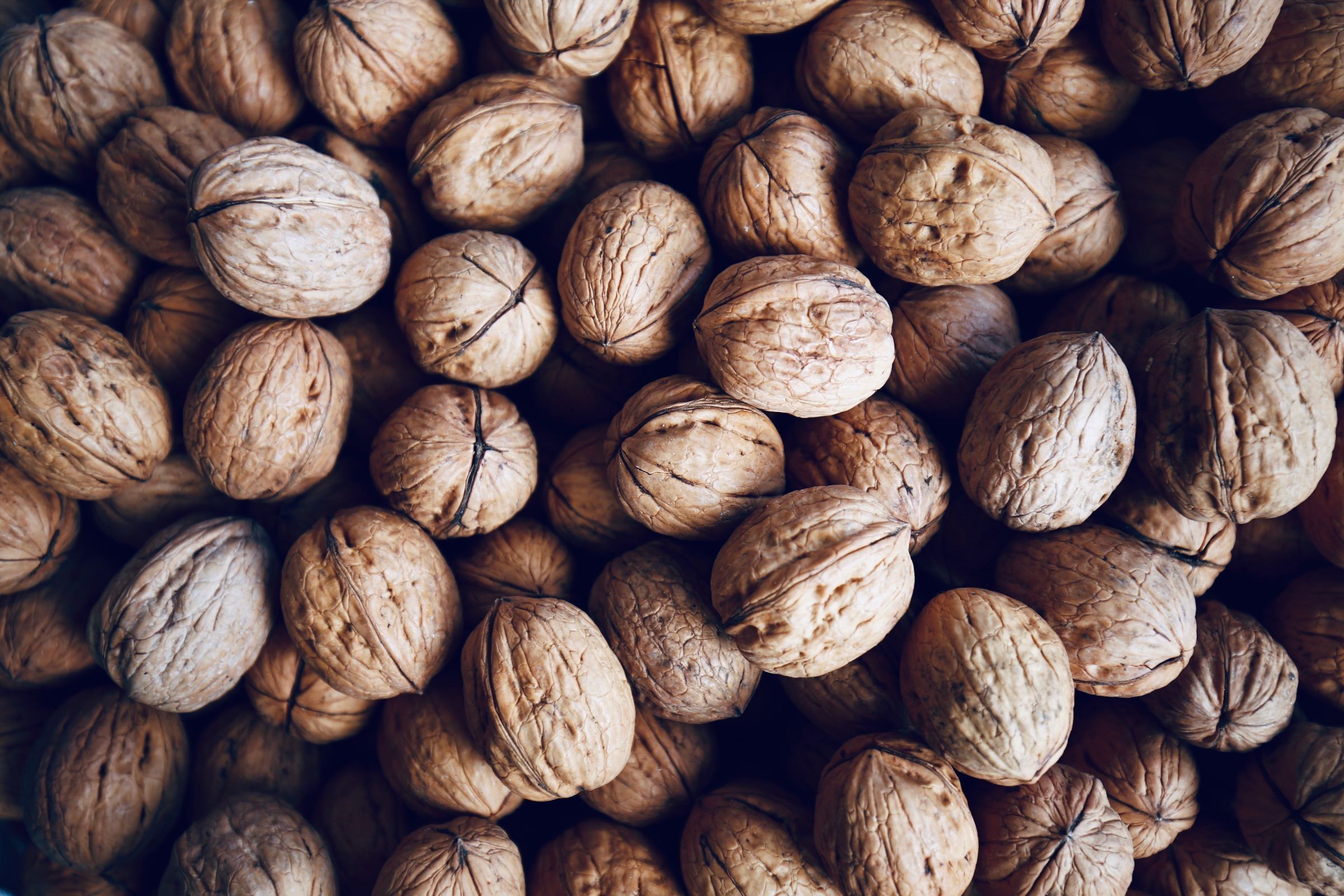 Many whole walnuts in shells packed together.