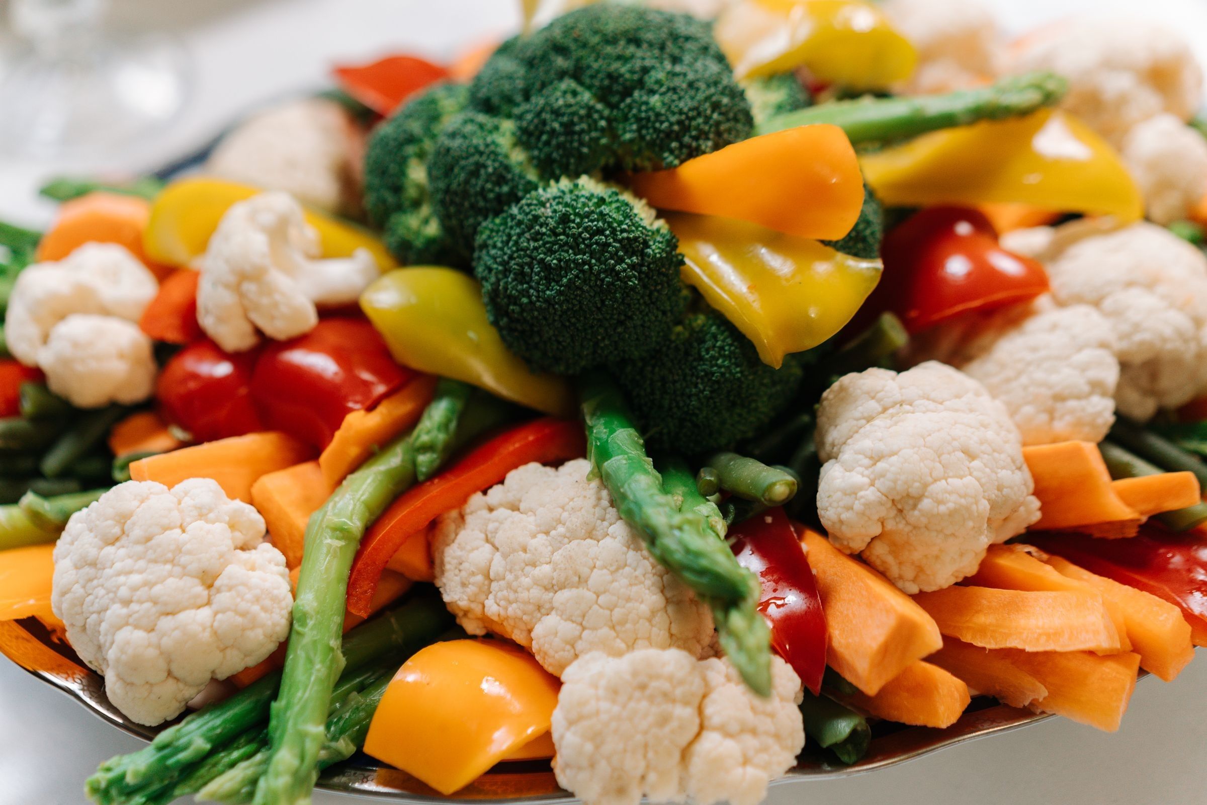 A platter of broccoli, cauliflower, carrot slices, green beans and red and yellow peppers.