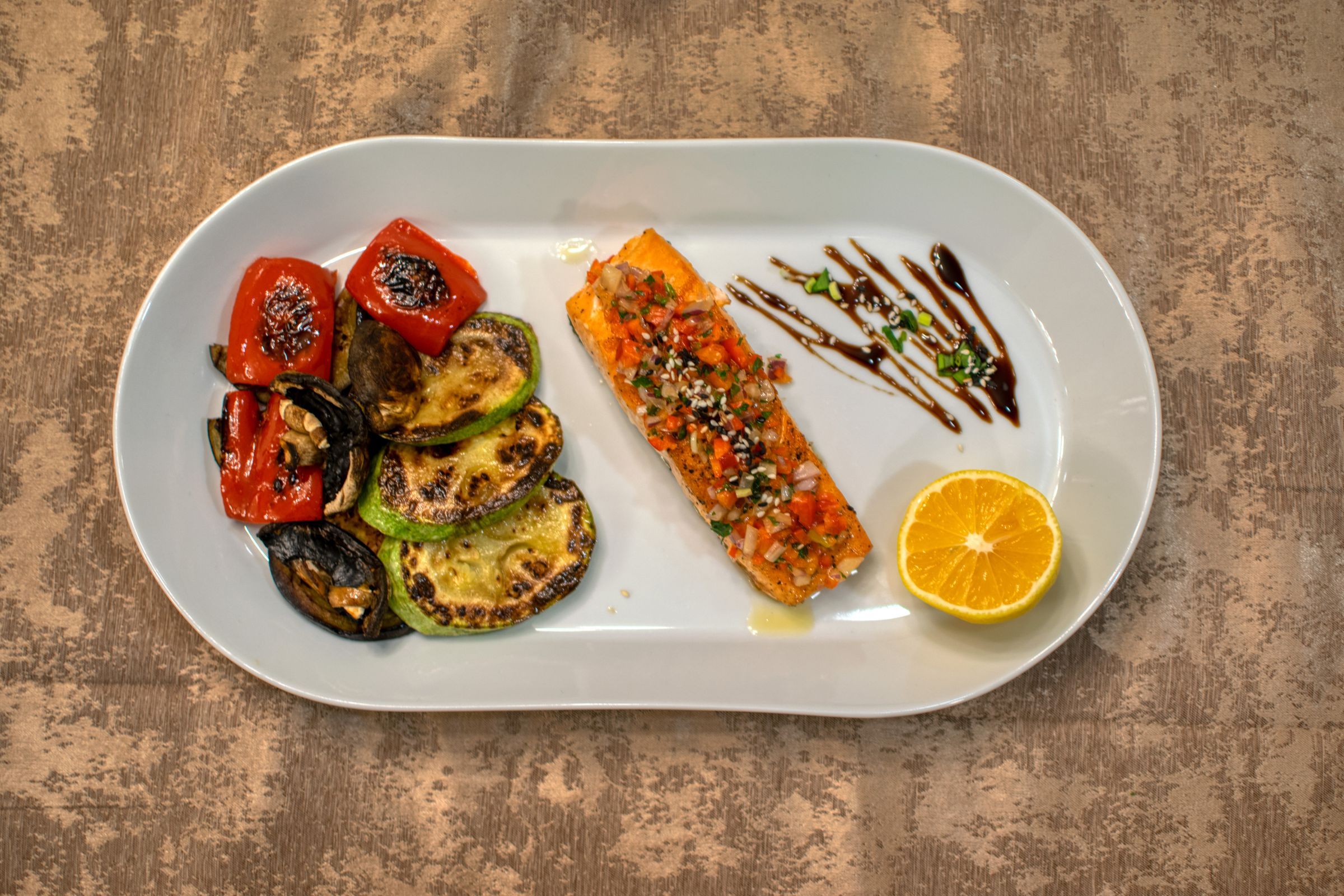 Grilled salmon with roasted vegetables and a lemon slice