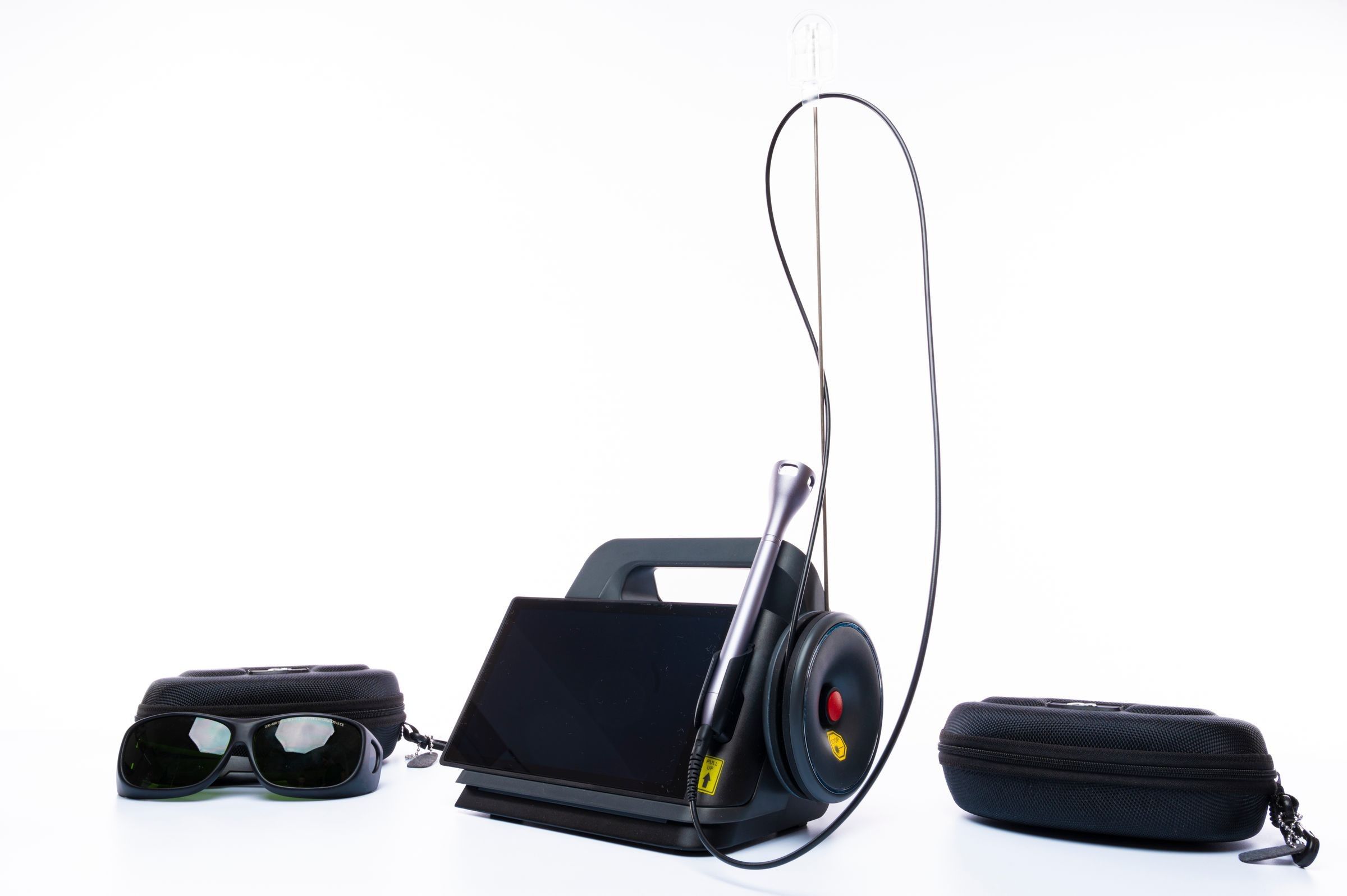 A black laser treatment unit with a handheld applicator on a cable, and a pair of protective goggles in a case, on a white background.