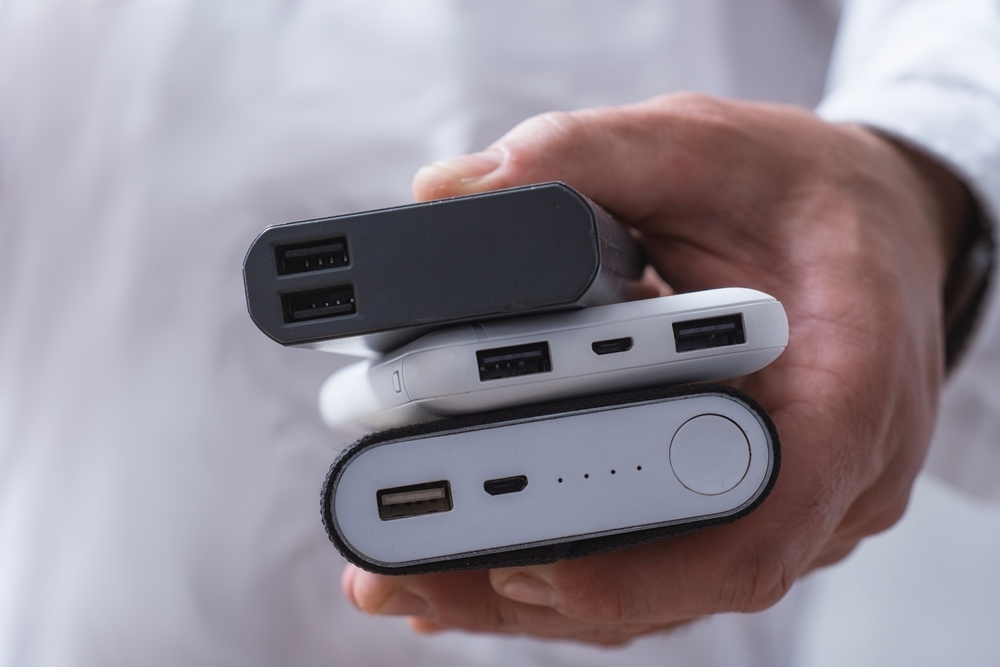 Image Person holds three portable power banks stacked in one hand, showing USB charging ports and indicator lights