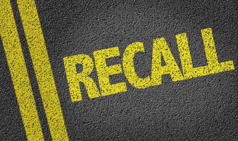 Yellow recall warning text on asphalt road symbolizing Toyo Open Country A/T III tire recall and tread separation safety risk