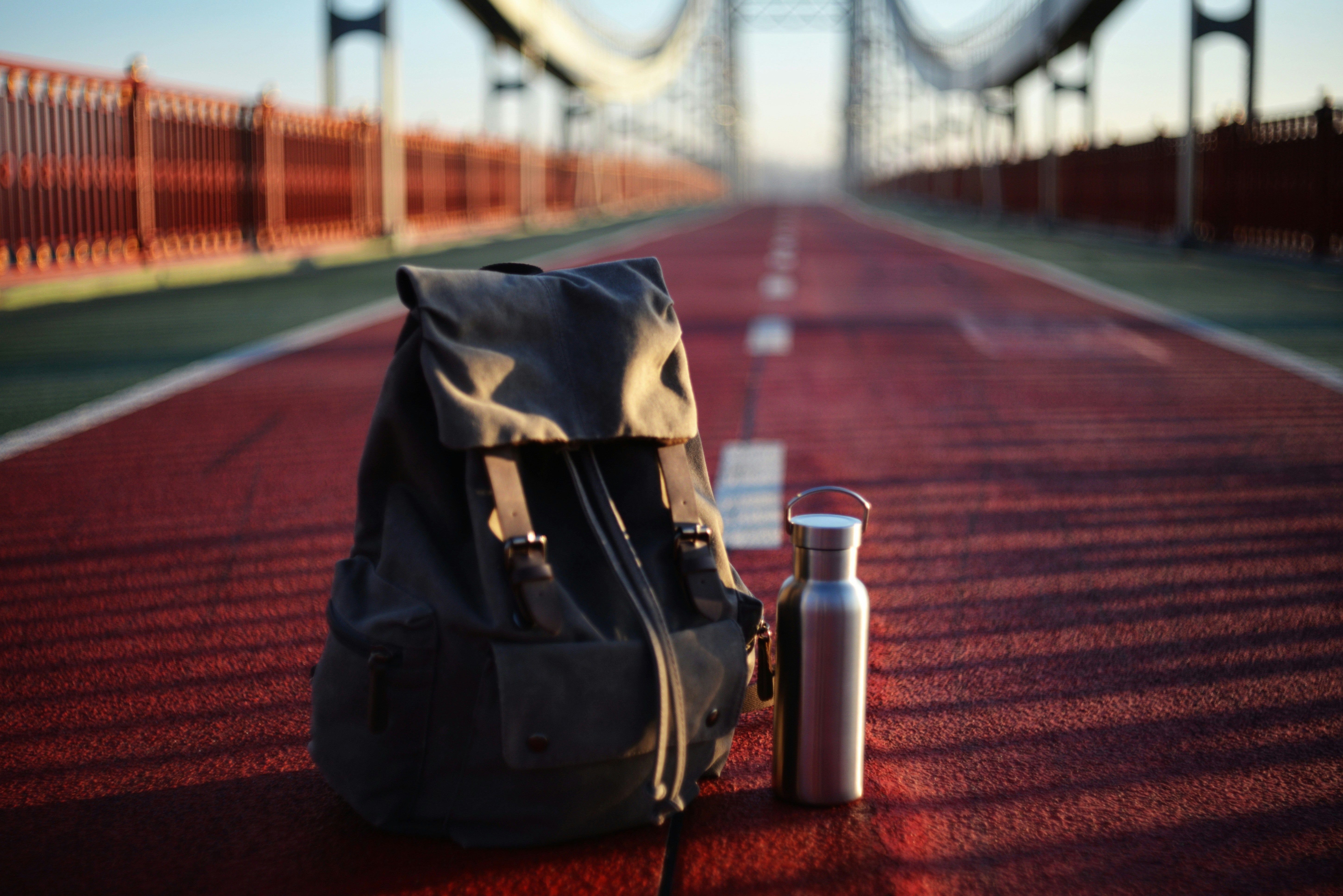 A backpack and metal bottle on an empty bridge, symbolizing the Thermos recall and the everyday products that may pose hidden injury risks.