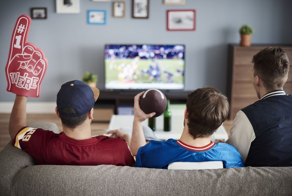 Friends watching the Super Bowl at home before heading out, highlighting the risk of Super Bowl accidents caused by impaired and distracted driving