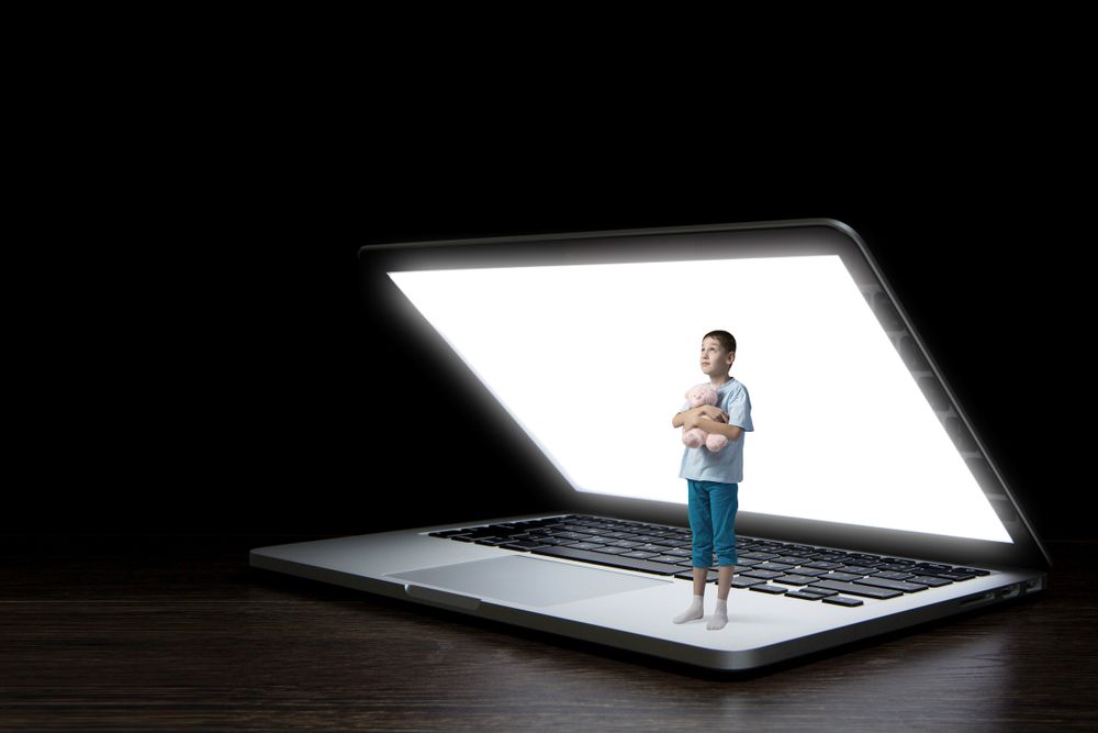 Child standing inside glowing laptop symbolizing online dangers for kids and the debate over the KIDS Act and Big Tech accountability