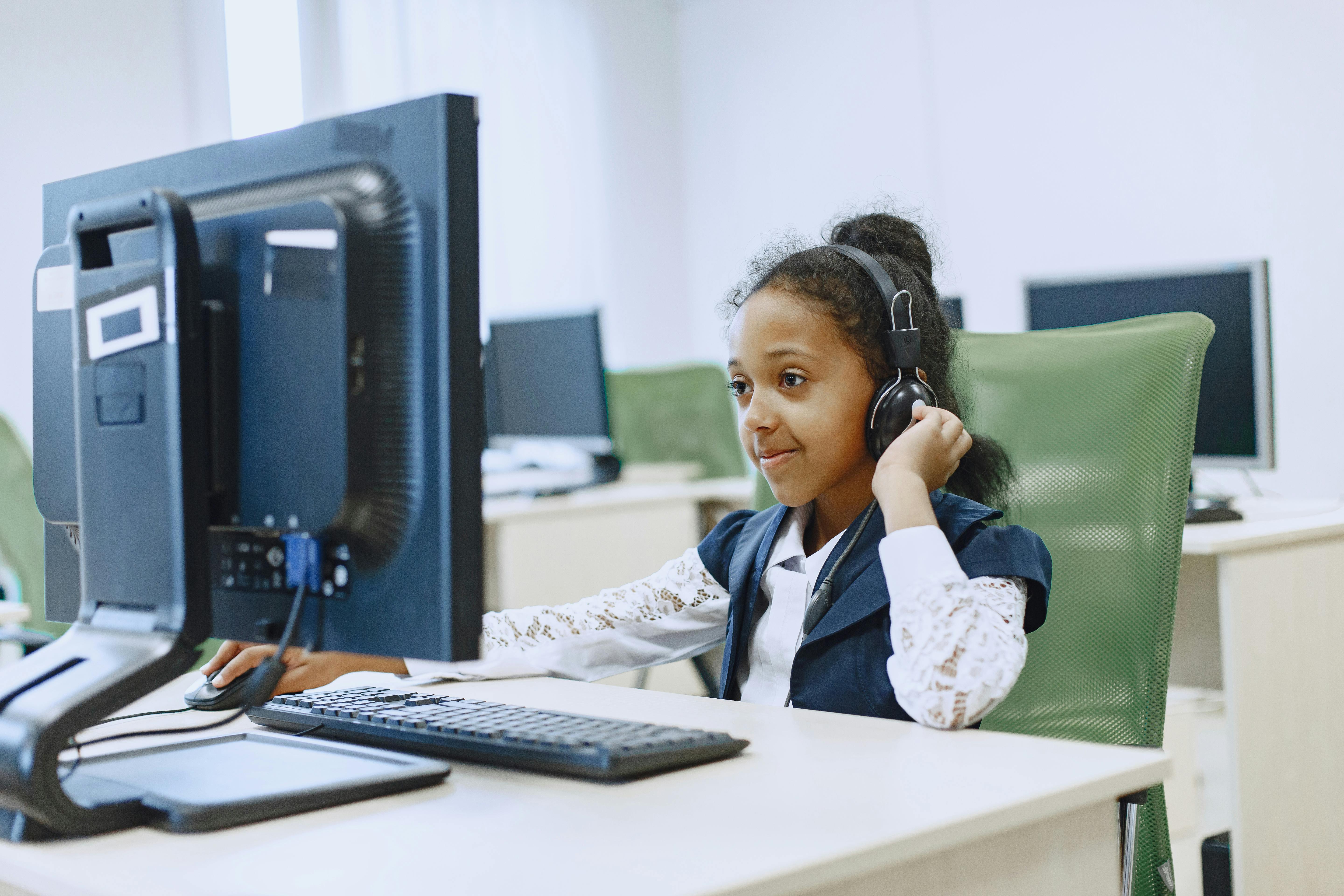 Young child wearing headphones while using a computer, highlighting concerns about online gaming safety and predator risks on Roblox.