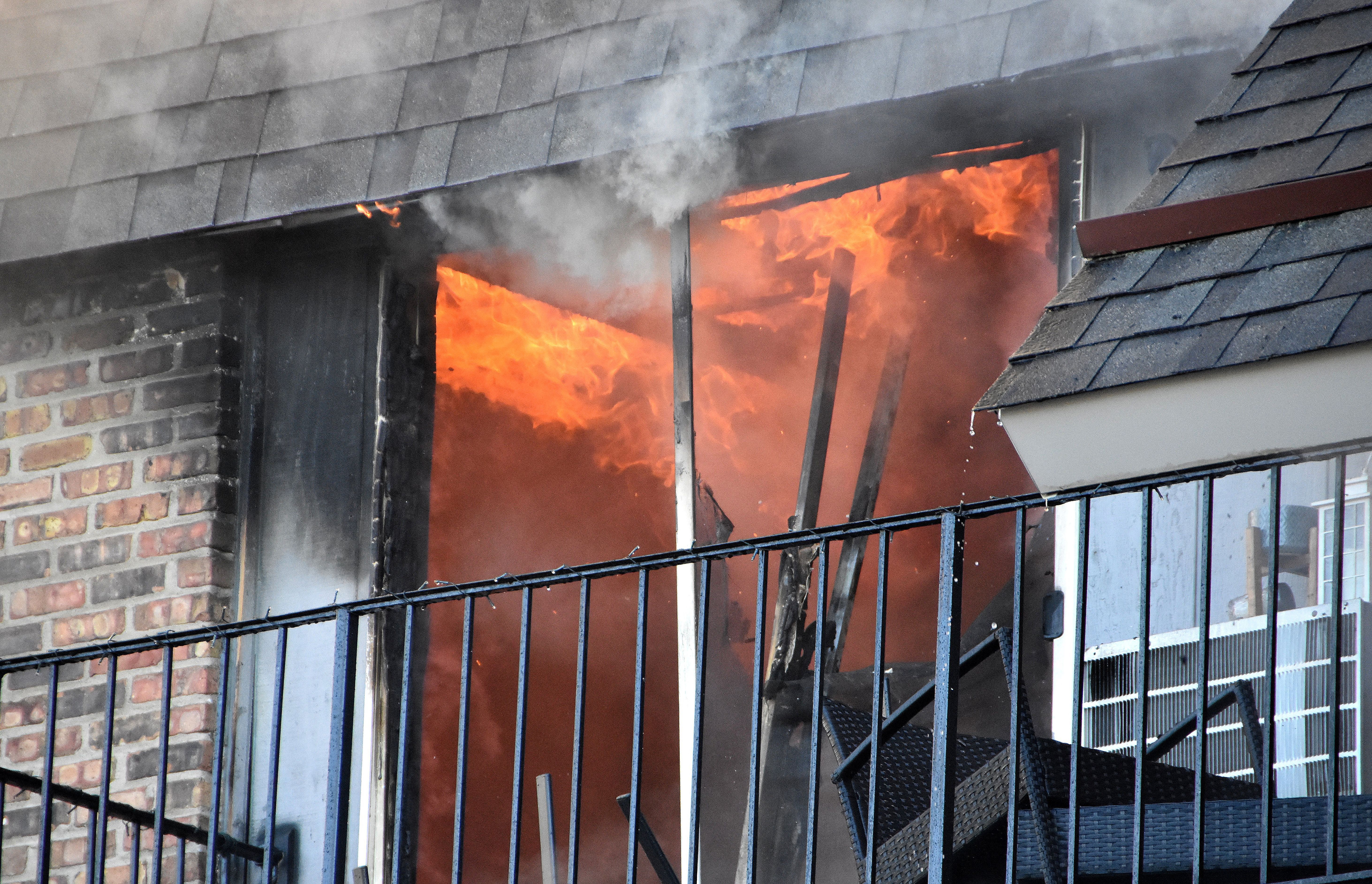 Flames and smoke pouring from the upper-floor window of an apartment building, representing an apartment fire