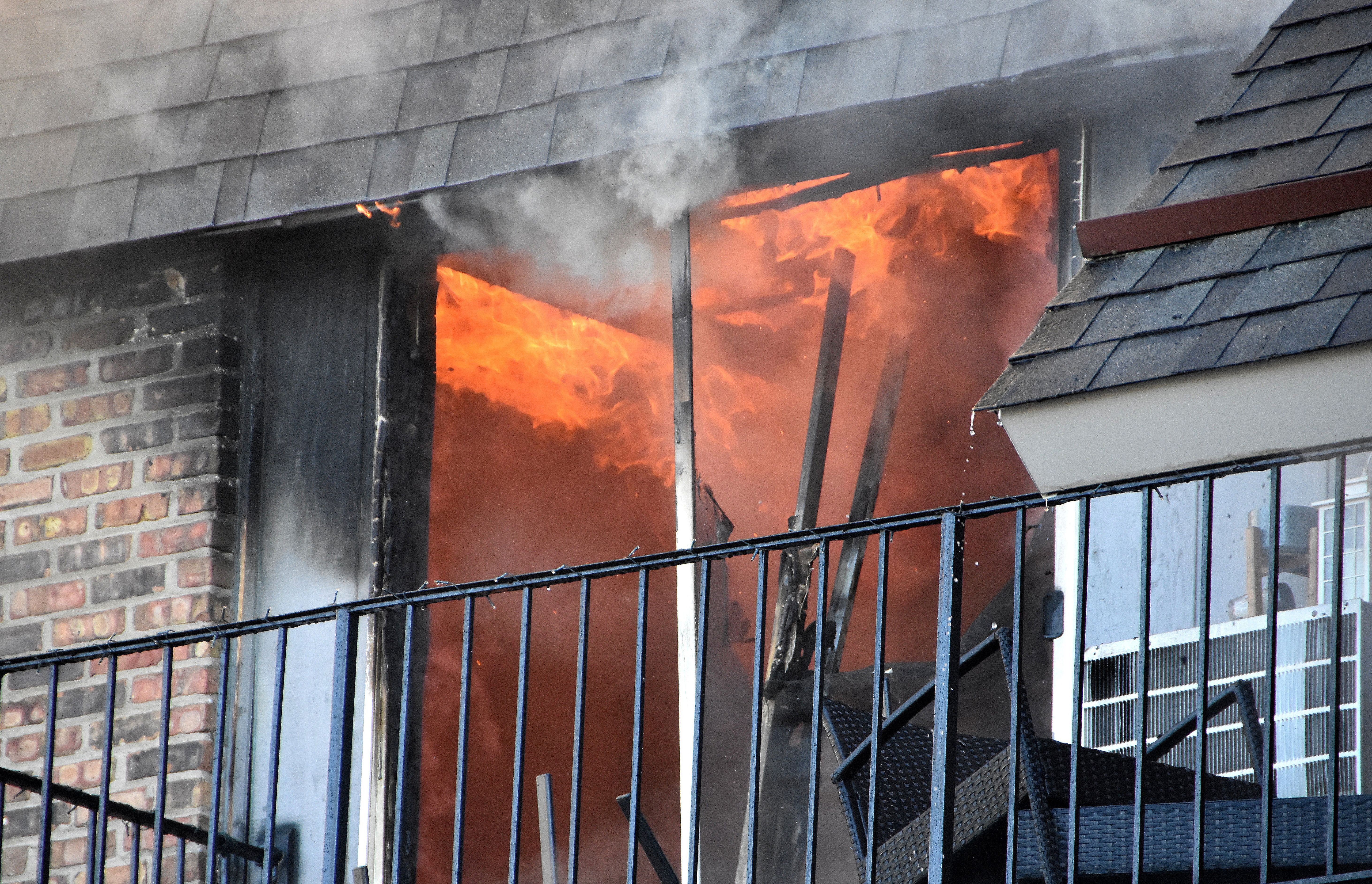 Image Flames and smoke pouring from the upper-floor window of an apartment building, representing an apartment fire